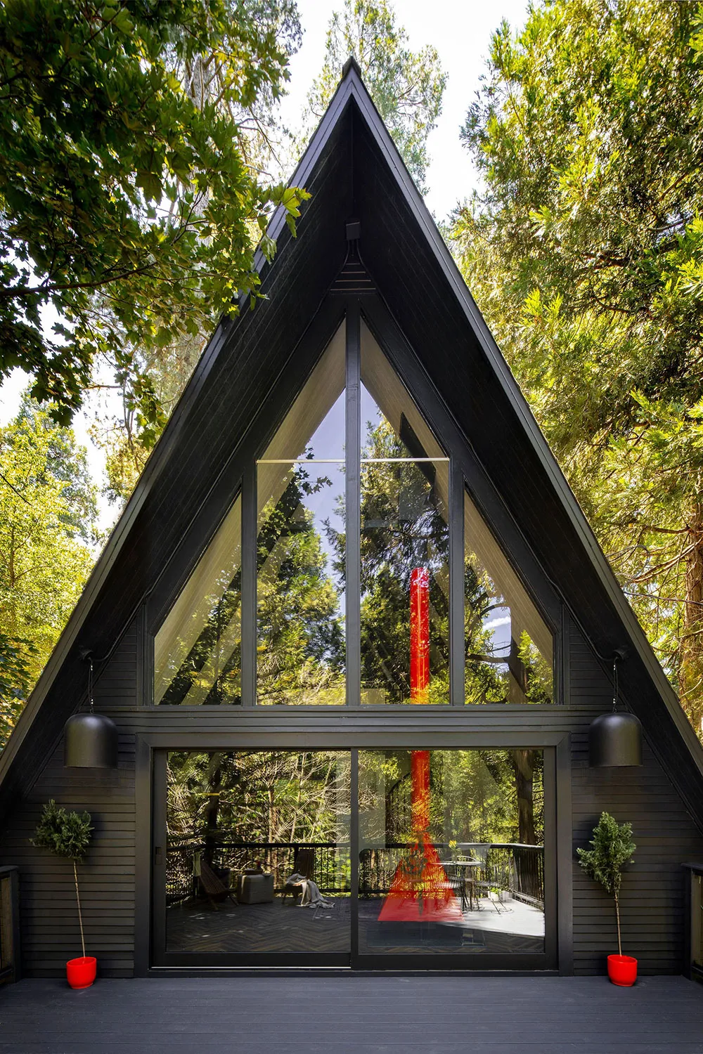 Accents noirs et cheminée rouge : une maison en forme de A dans la forêt - Gallery image 1