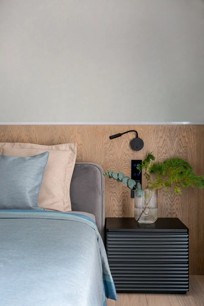 La pared al cabezal de la cama en el dormitorio está cubierta con una estuco decorativo que recrea la textura de la piedra.