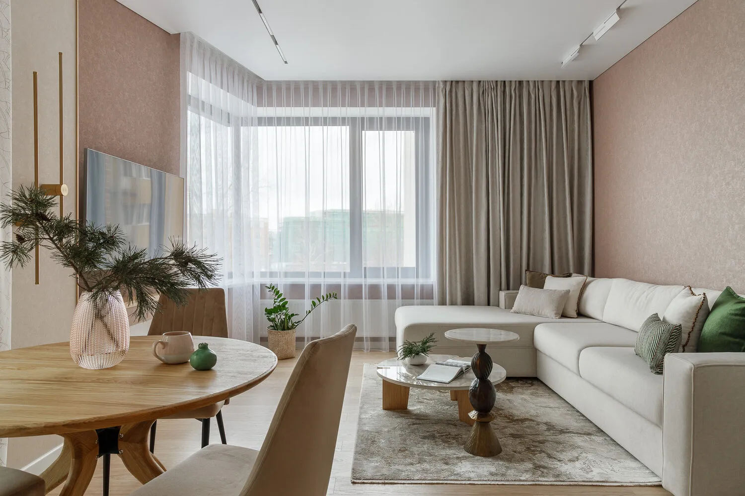 En la sala de estar, se usaron cortinas complementarias en dos ventanas. En la ventana panorámica que da al balcón cuelga una cortina de encaje con hojas, mientras que en la ventana angular del área del sofá se colocaron cortinas de tela densa, y en el dormitorio una manta hecha con la misma tela.