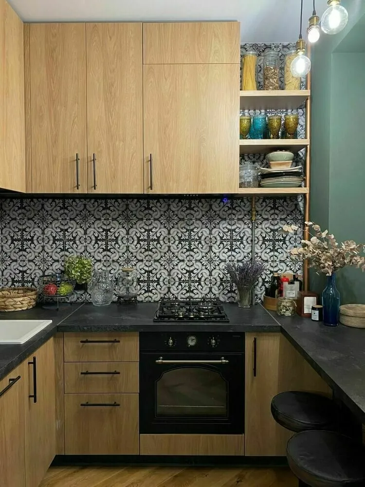 La zona de comedor está marcada con un color verde profundo y decorada como una barra que se convierte en extensión de la encimera. Encima hay un luminario colgante original.