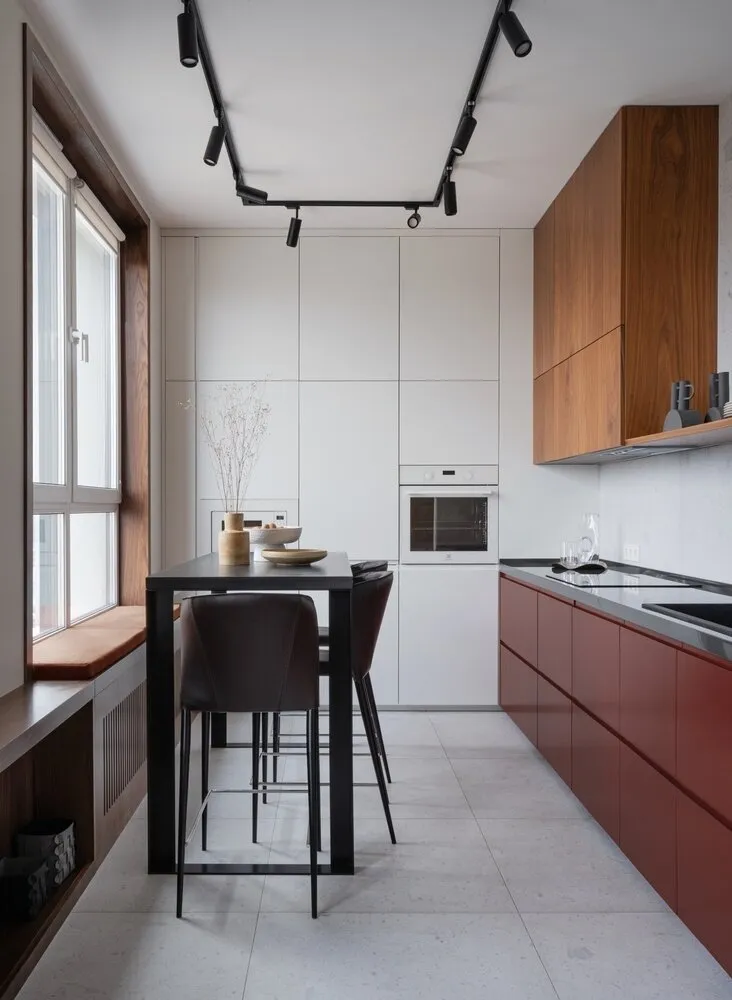 Casi toda la mobiliario en nuestros proyectos se realiza bajo medida. En la cocina usamos almacenamiento cerrado. Una de las paredes está completamente dedicada a un armario desde el suelo hasta el techo. Pero decidimos dejar una estantería abierta que añade ligereza y geometría