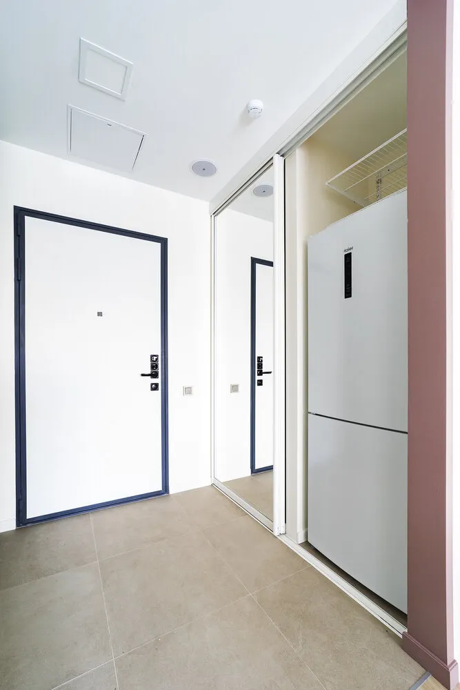 Lo inusual fue elegir el lugar del refrigerador, que se colocó en una repisa tras una puerta espejo corredera. Esto permitió ahorrar presupuesto y adquirir un modelo independiente, además de retirar el refrigerador del área principal de la cocina-comedor.