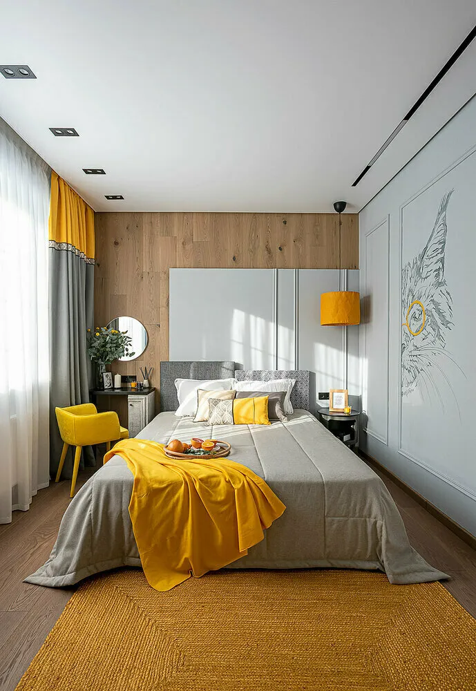 Cabecera de la cama dividida en dos partes: una parte más alta, otra más baja, una gris, otra con estampado vegetal. Cama con colchón ortopédico alto.