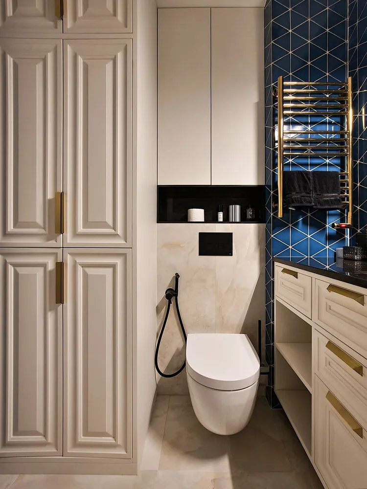 Según la estética del diseño del baño, se logró un aspecto elegante. El azulejo brillante azul crea un fondo donde los tonos claros parecen delicados, mientras que la fijación negra (grifos y cortinas) se ve juguetona e intrigante. Añadir detalles dorados completa la imagen y la hace más rica.