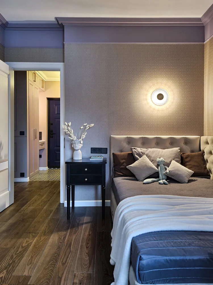 En la habitación infantil se usaron papel pintado de felpa fabricado por la empresa rusa Loymina. Aunque parecen oscuros, actúan como fondo neutro donde la mueble clara luce más definida. La repisa negra, por otro lado, resalta y revela el color y la complejidad de los papeles pintados. El pequeño motivo en forma de rombo crea una atmósfera acogedora en la habitación. El borde púrpura alrededor de toda la habitación complica y enriquece el espacio.