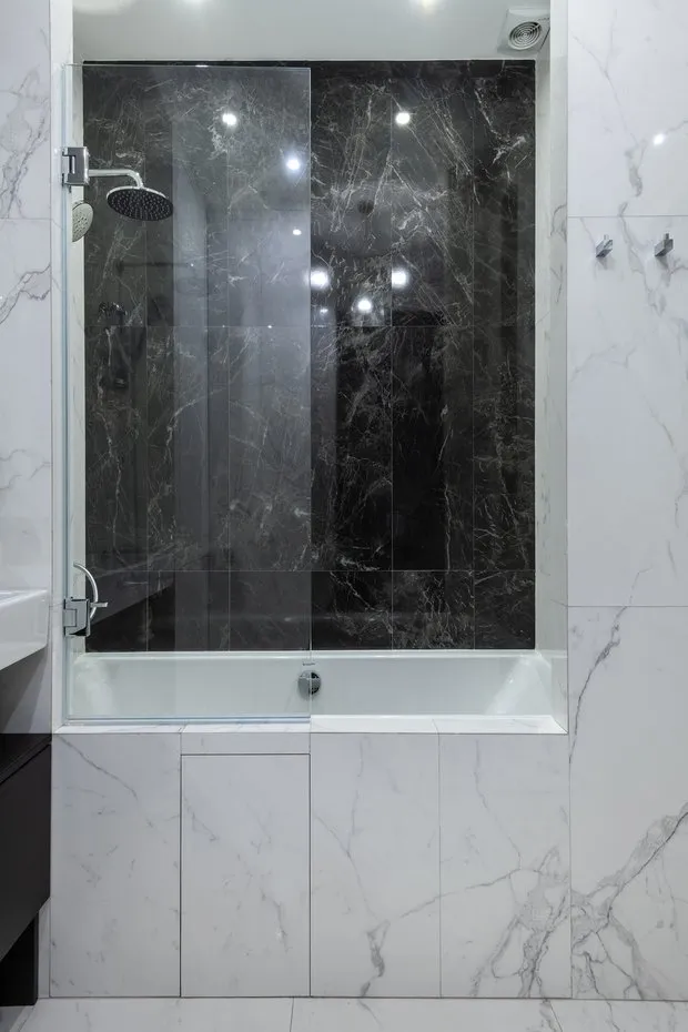 En el baño, a la izquierda del lavabo detrás de un divisor se encuentra la lavadora con fachadas de muebles.