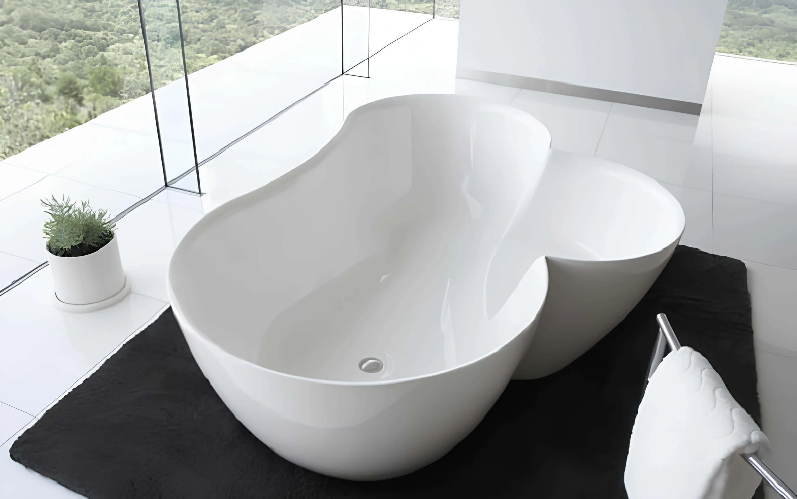Modern sculpted bathtub with curved organic design overlooking lush greenery