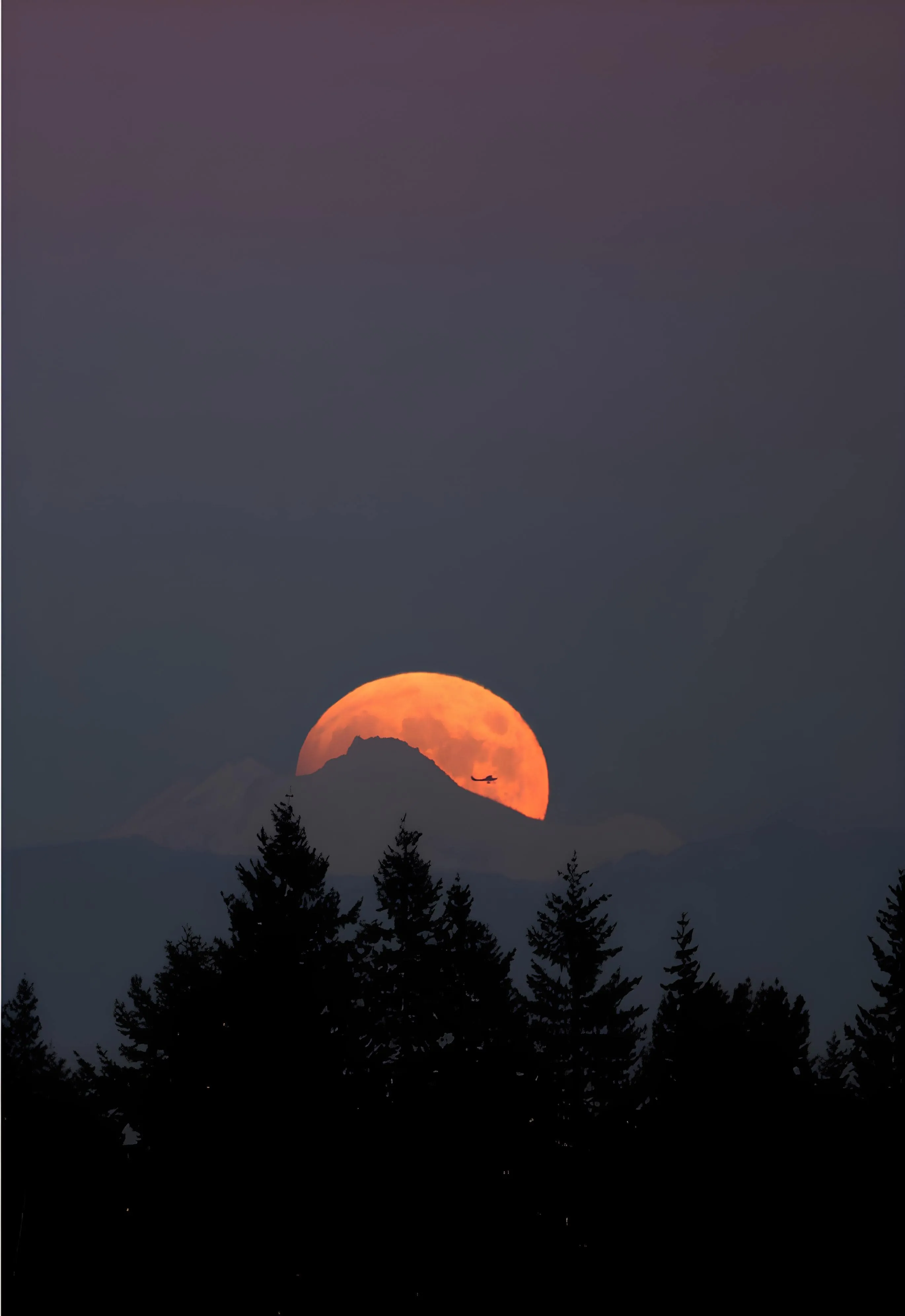 Full moon rising above mountain ridges