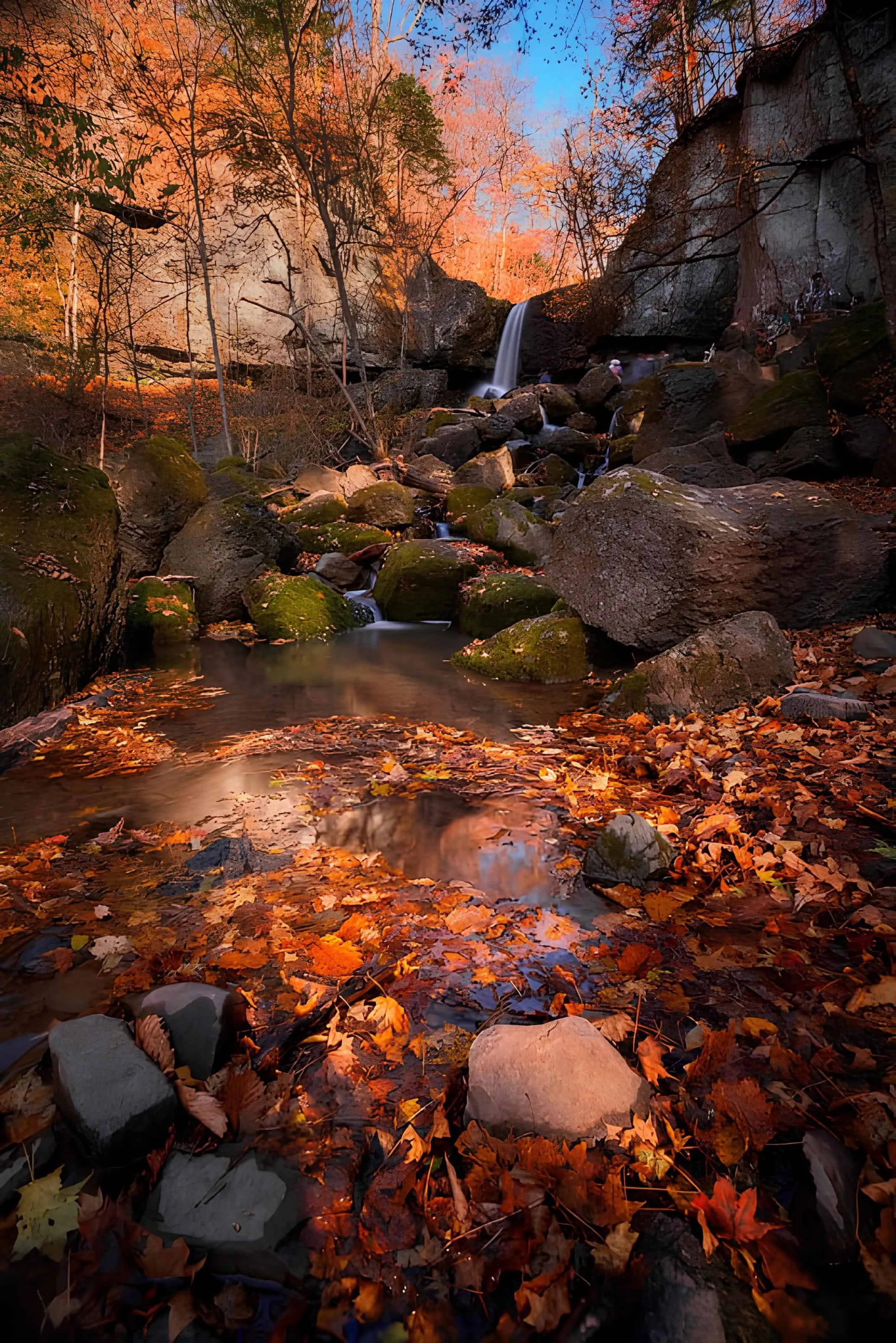 Waterfall flowing through red autumn leaves and stone outcrops