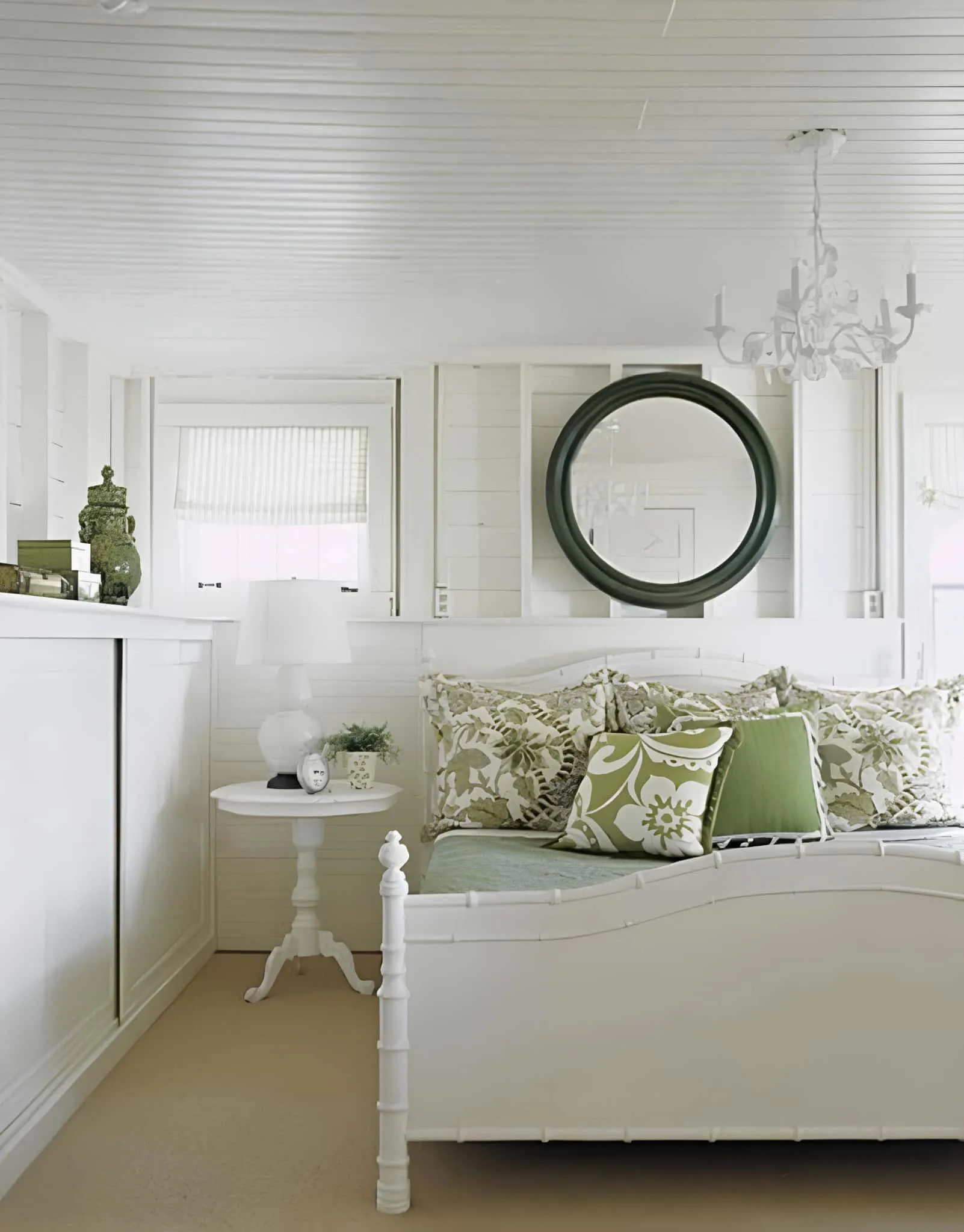 配有绿色花卉枕头和圆形镜子的白色卧室