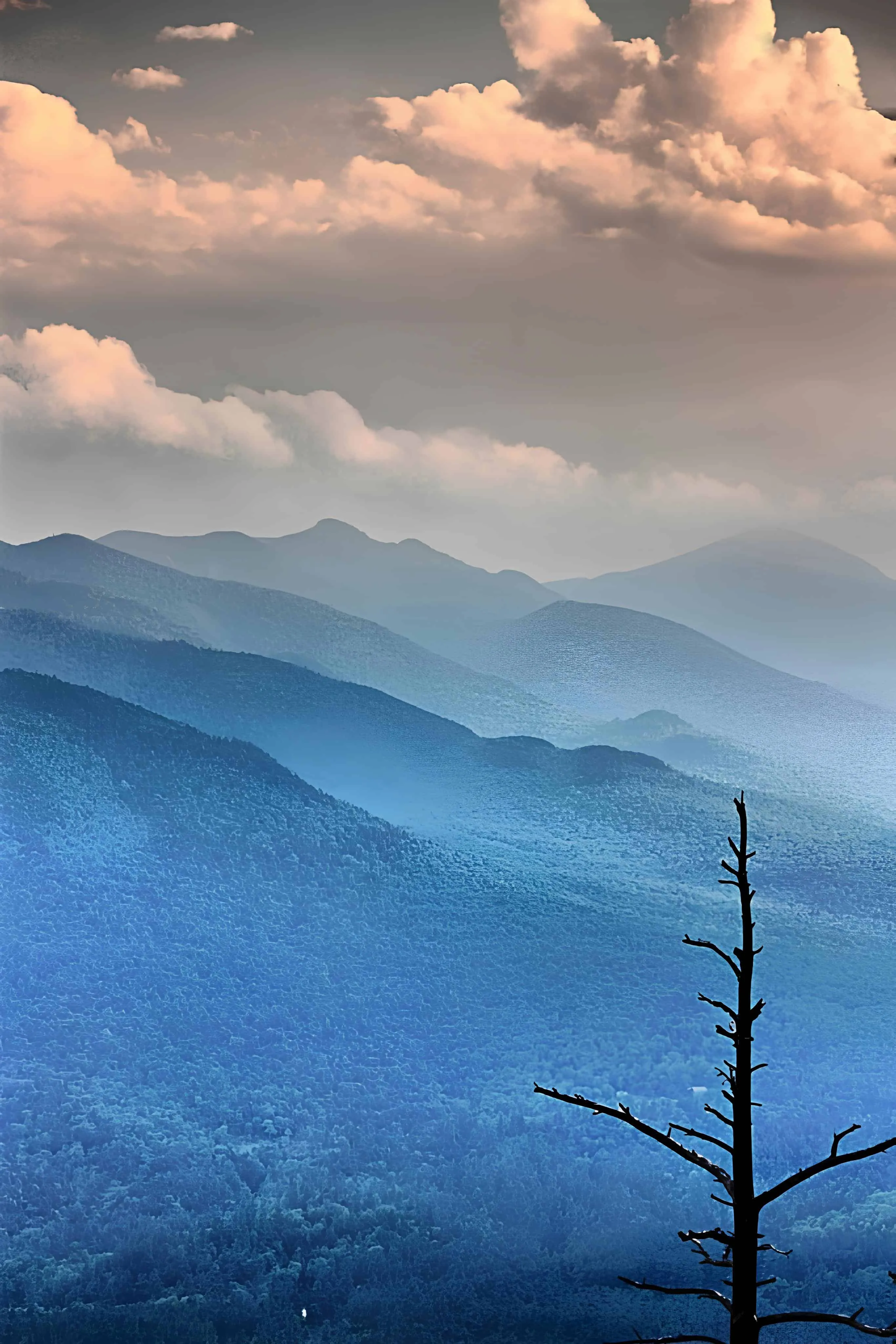 Several mountain ranges disappearing into the horizon under dramatic clouds