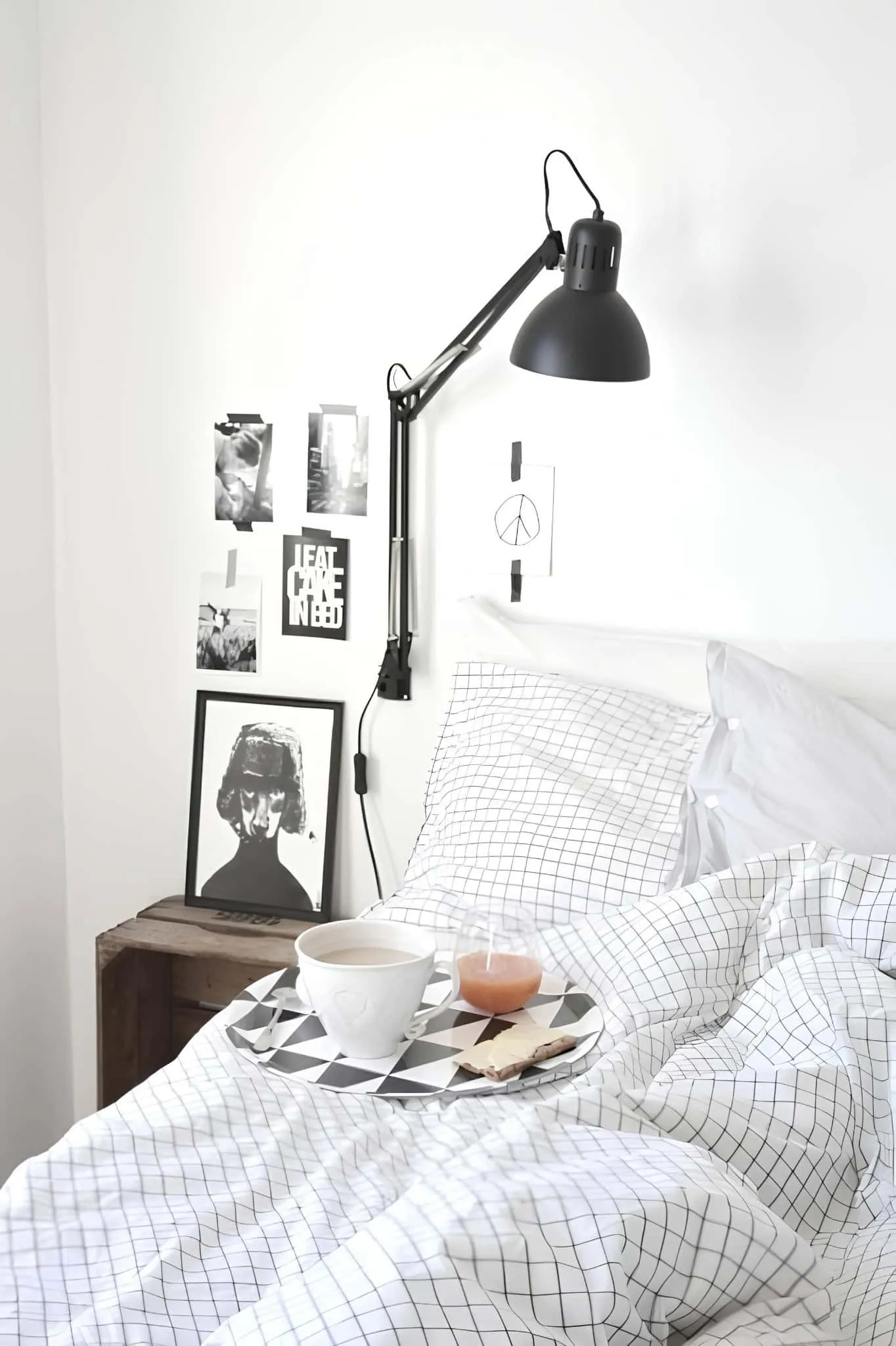 配有网格床品、黑色壁灯和早餐盘的斯堪的纳维亚白色卧室