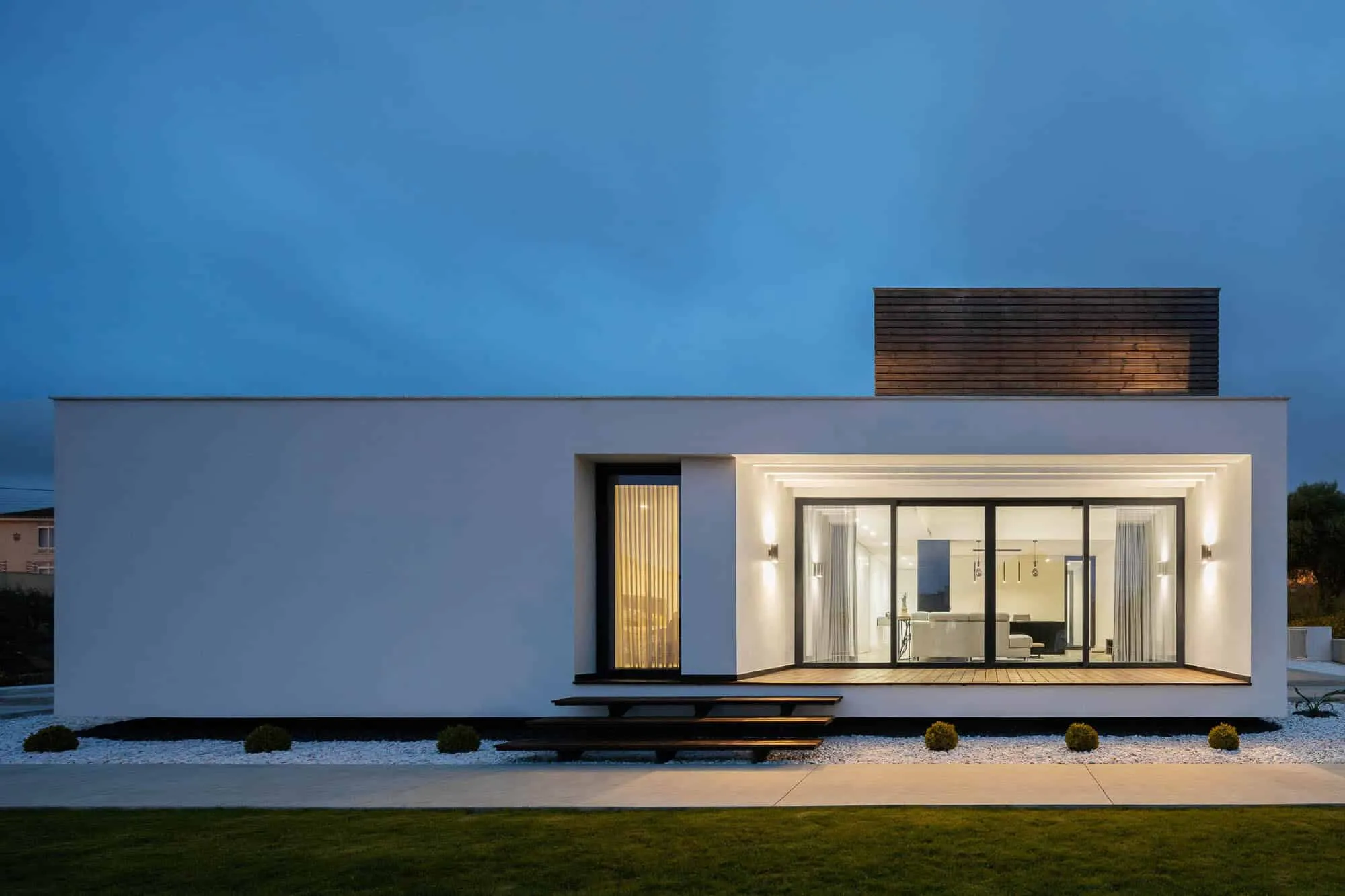 Modern minimalist house with elegant white facade, large glass windows and contemporary design elements at night