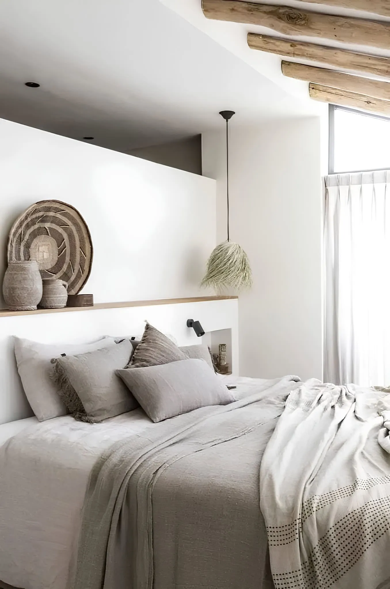 配有柔和色调、木质天花板横梁与手工编织装饰的卧室。