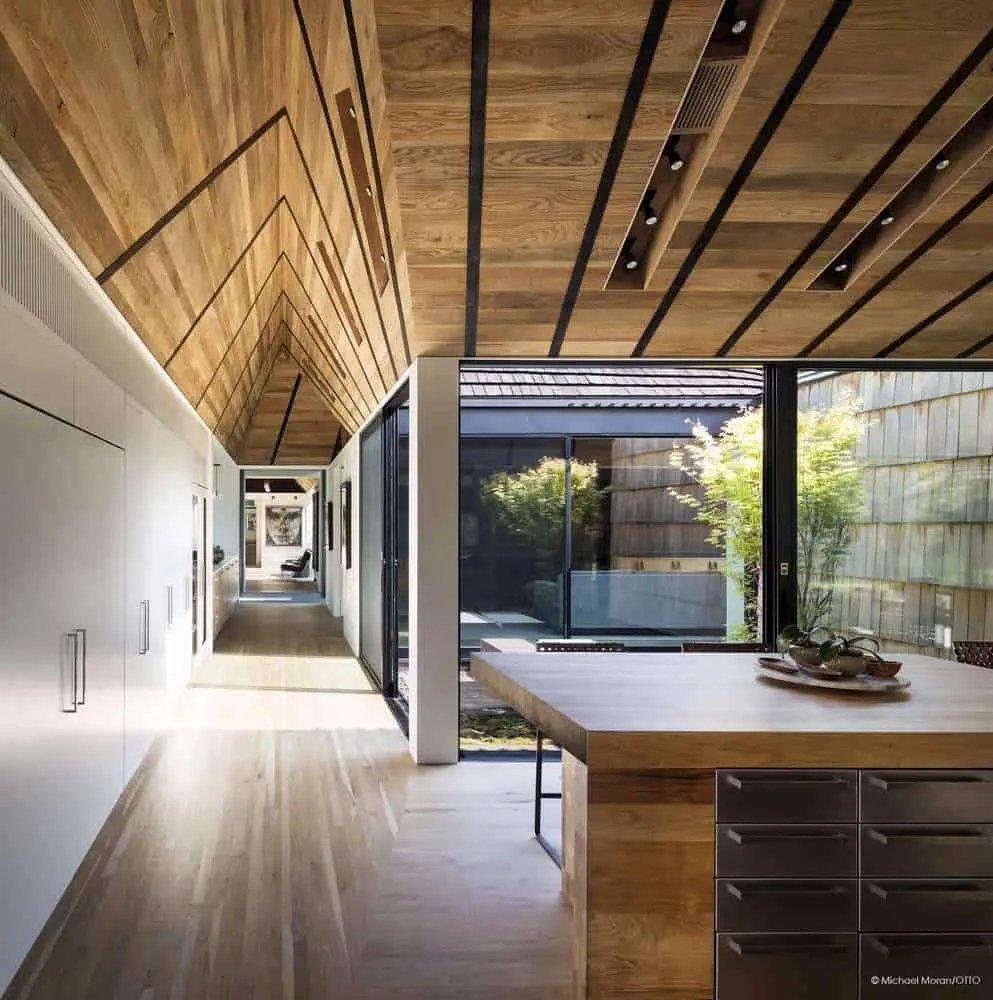 Kitchen corridor with natural light and angled wooden ceiling.