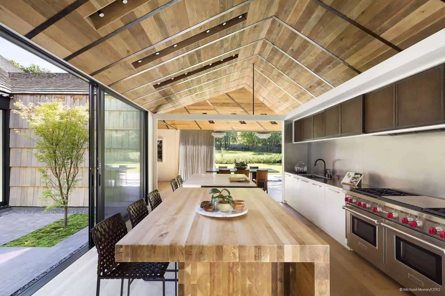 Modern kitchen with wooden ceiling and open layout to dining area.