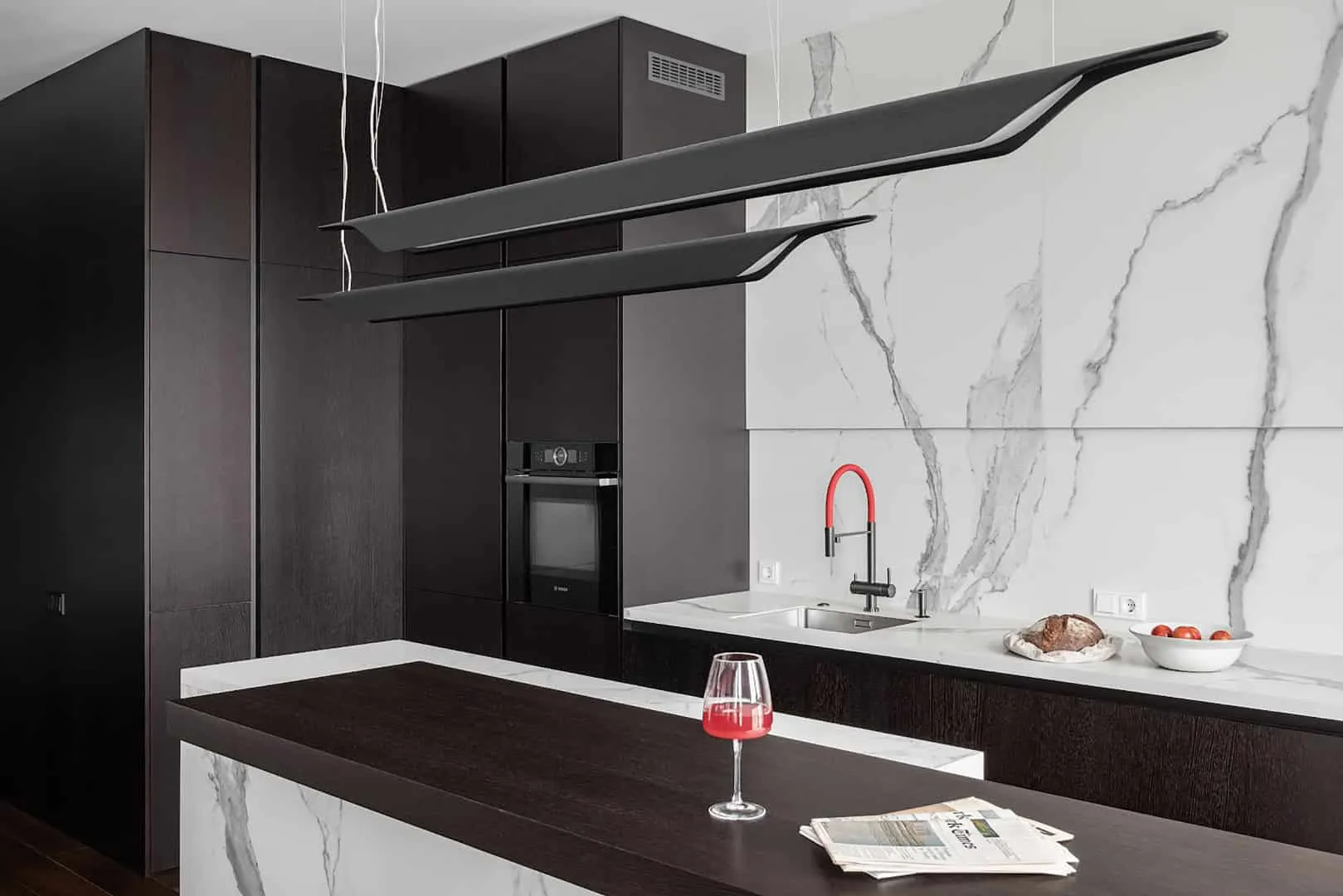 Spacious room centered around a marble island and multi-layered lighting