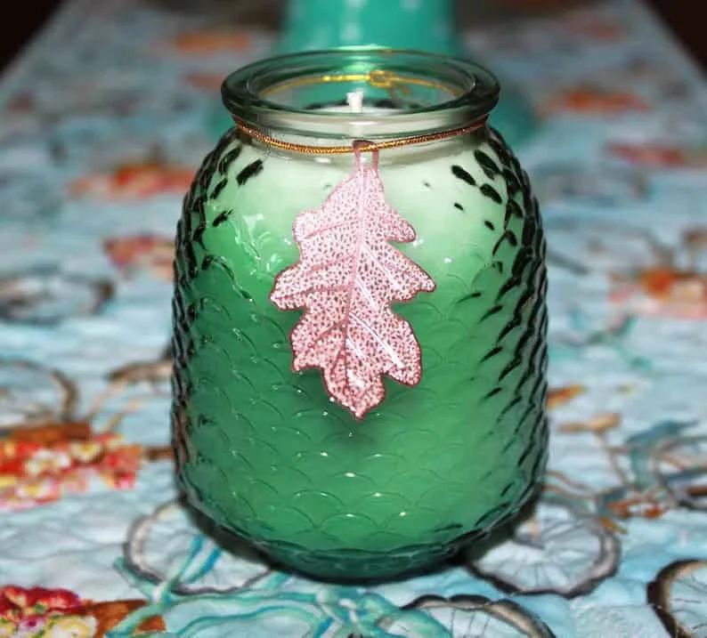 11. Vela verde con folio dorado en frasco de vidrio