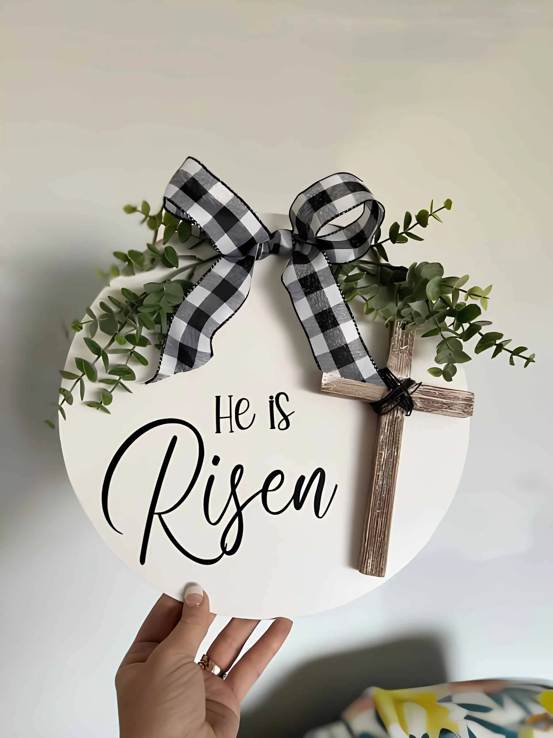 DIY señal de Easter con texto 'Él Resucitó' en negro sobre fondo blanco, decorada con hierba, cinta de bufallo y cruz de madera - fe estilo granjero
