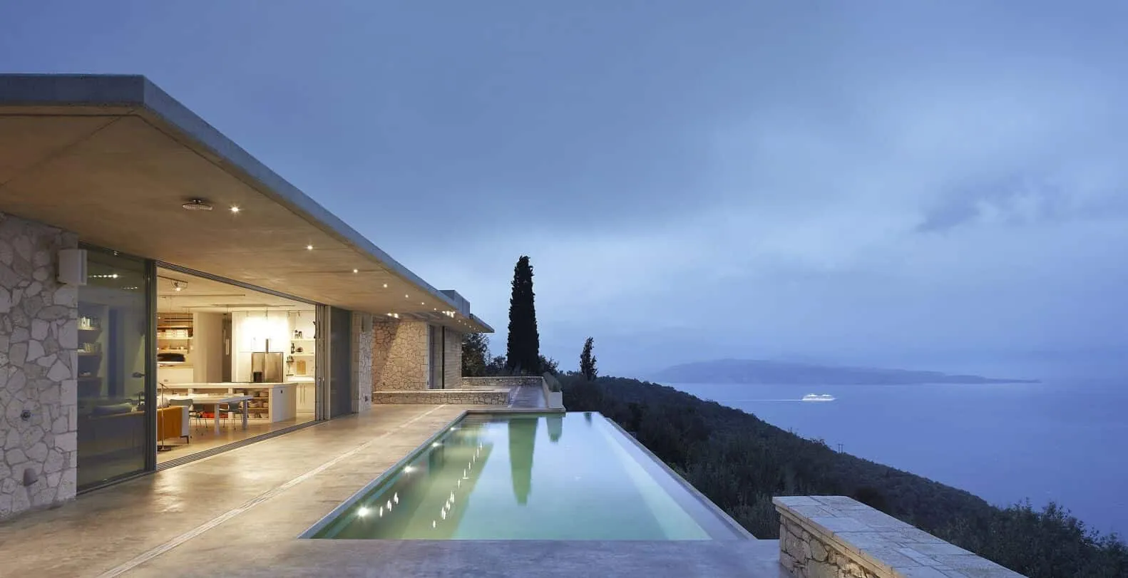 Modern luxurious house with endless swimming pool overlooking picturesque ocean view at dusk