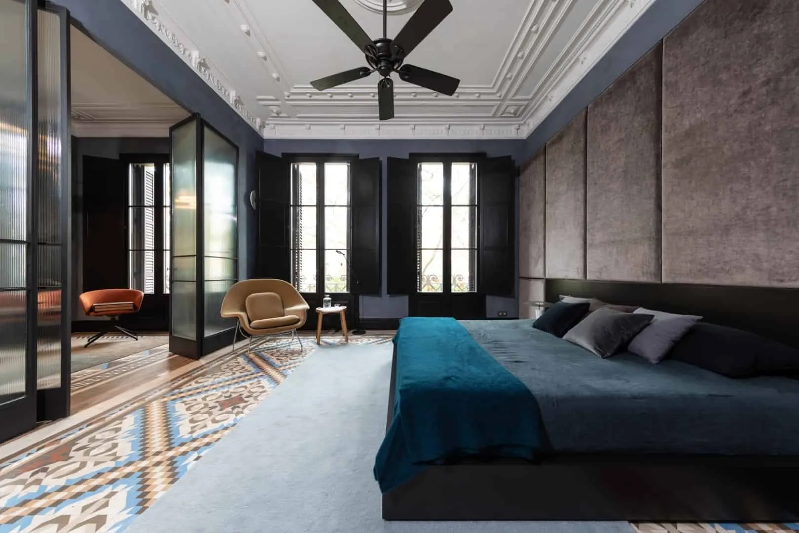 带有深色墙面、优雅天花板装饰、大窗户配黑色百叶窗、现代家具和图案瓷砖地板的豪华卧室，展现优雅建筑设计。