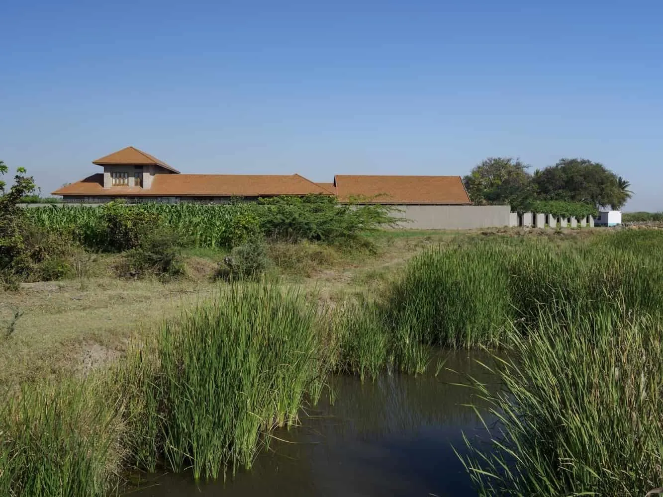 Passage with veranda, curving from front to rear courtyard and framing fields beyond.