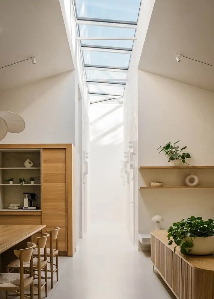 Night silhouette of low roof and eaves with warm interior light underneath.