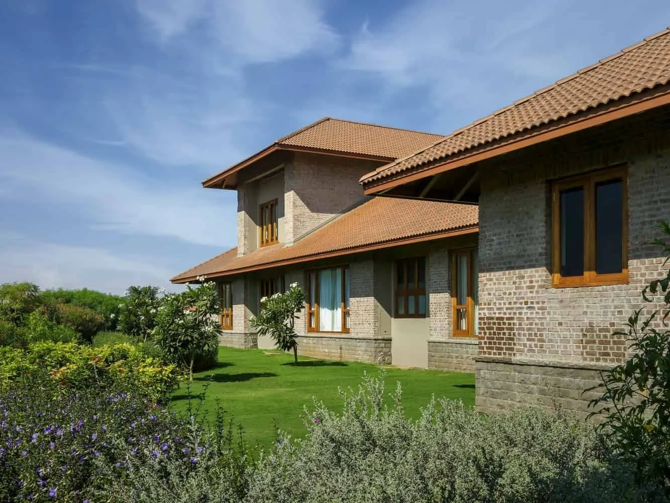 Shaded veranda between courtyard and garden, with stone mosaic and wooden overhangs.