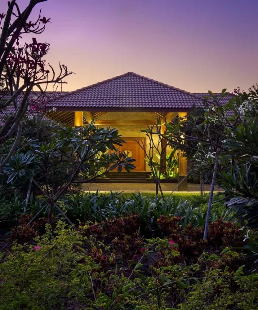 Living space opens onto a green courtyard with stone supports and wooden ceiling.