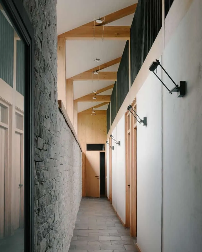 Hallway of bedroom with clerestories illuminating stone and wooden surfaces softly.