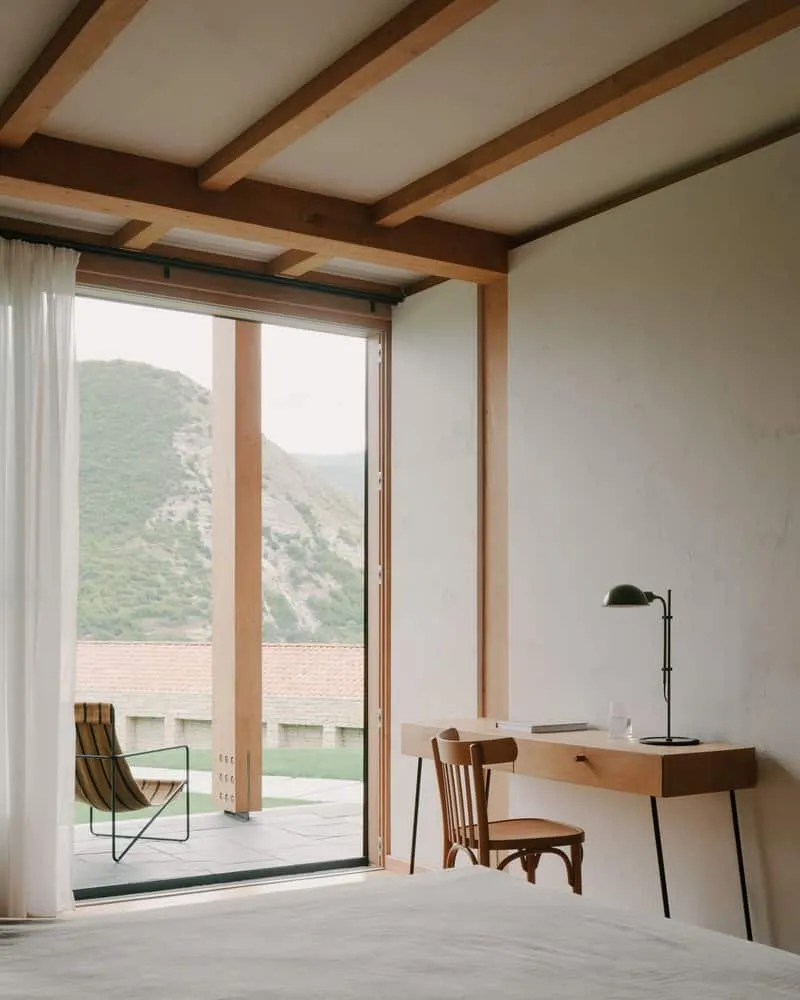 Dining room oriented toward hilly views, combining warm wooden ceilings with stained glass walls.