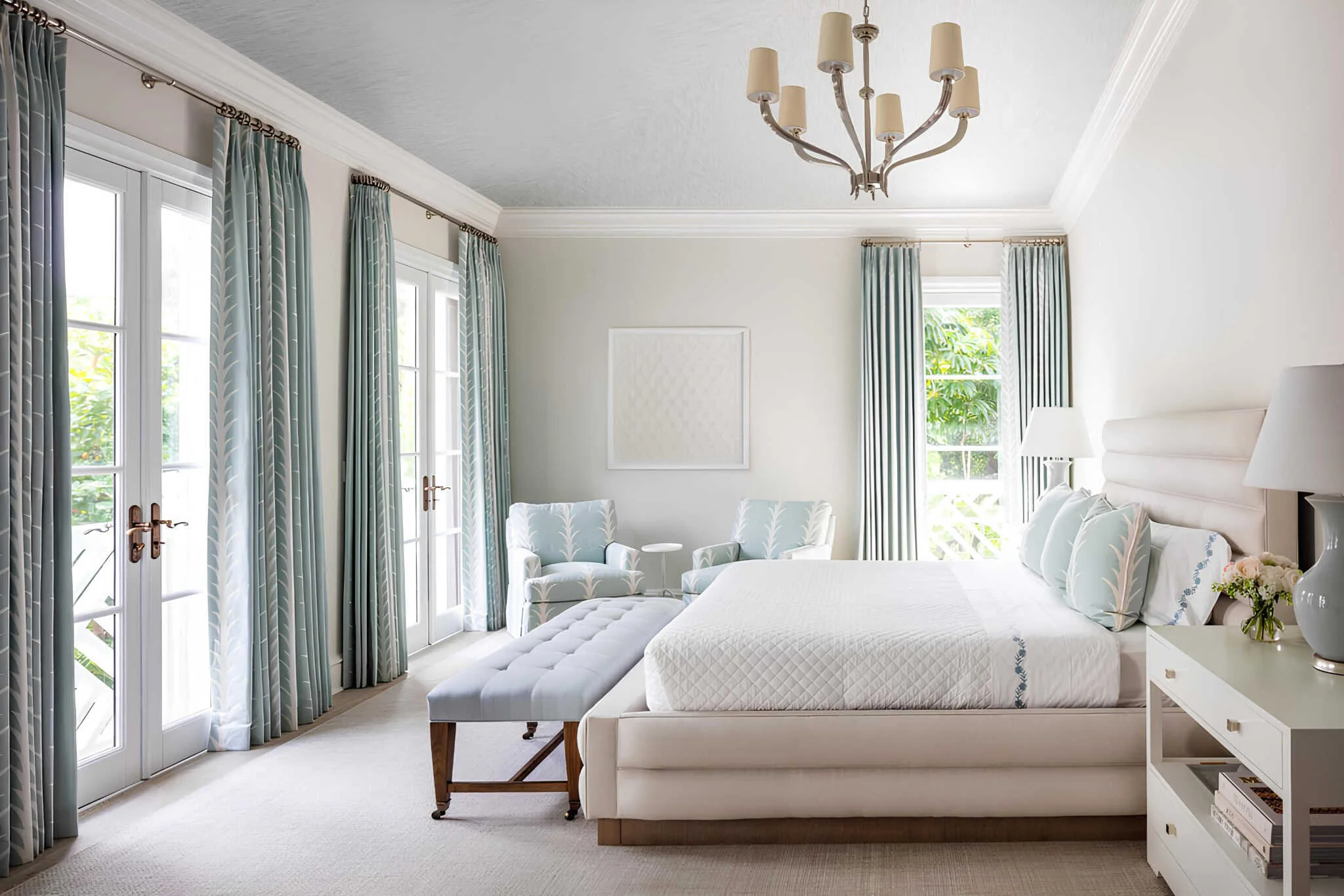 Dormitorio mediterráneo clásico con cortinas acuáticas, tapicería blanca y luminaria.