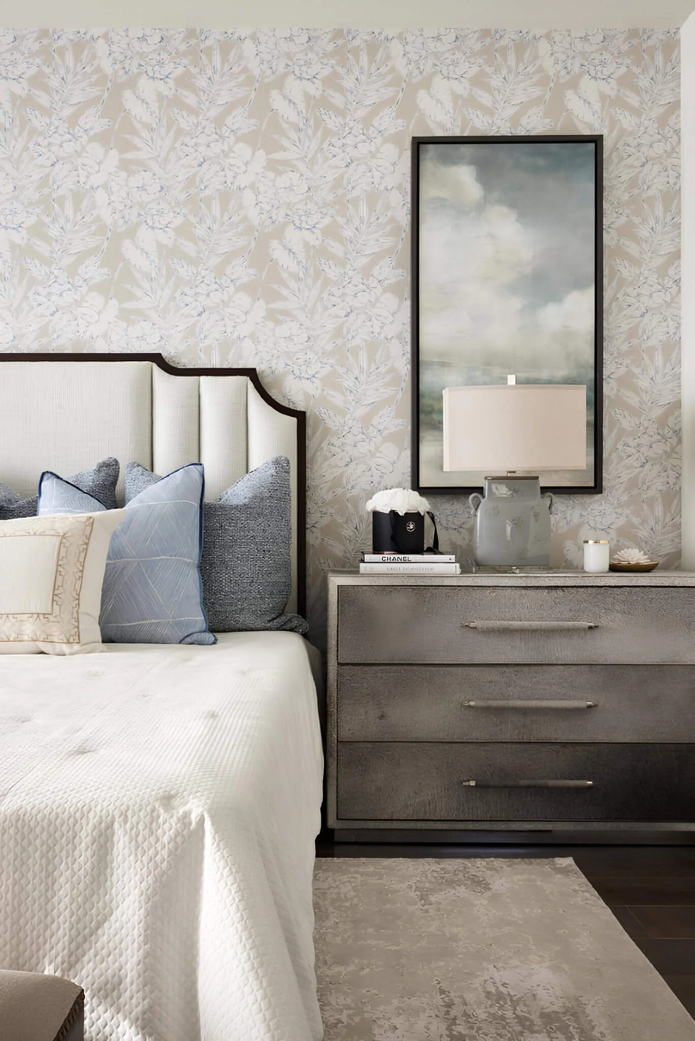 Dormitorio mediterráneo texturizado con papel pintado floral, almohadillas de diseñador y decoración en mesita.