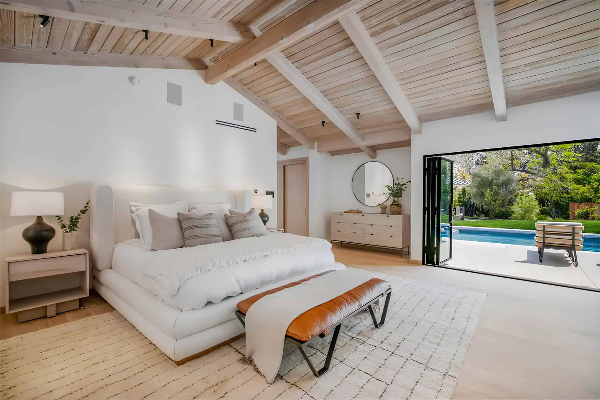 Dormitorio elegante con cabezal de cama oscuro bordado y ventana de pared completa.