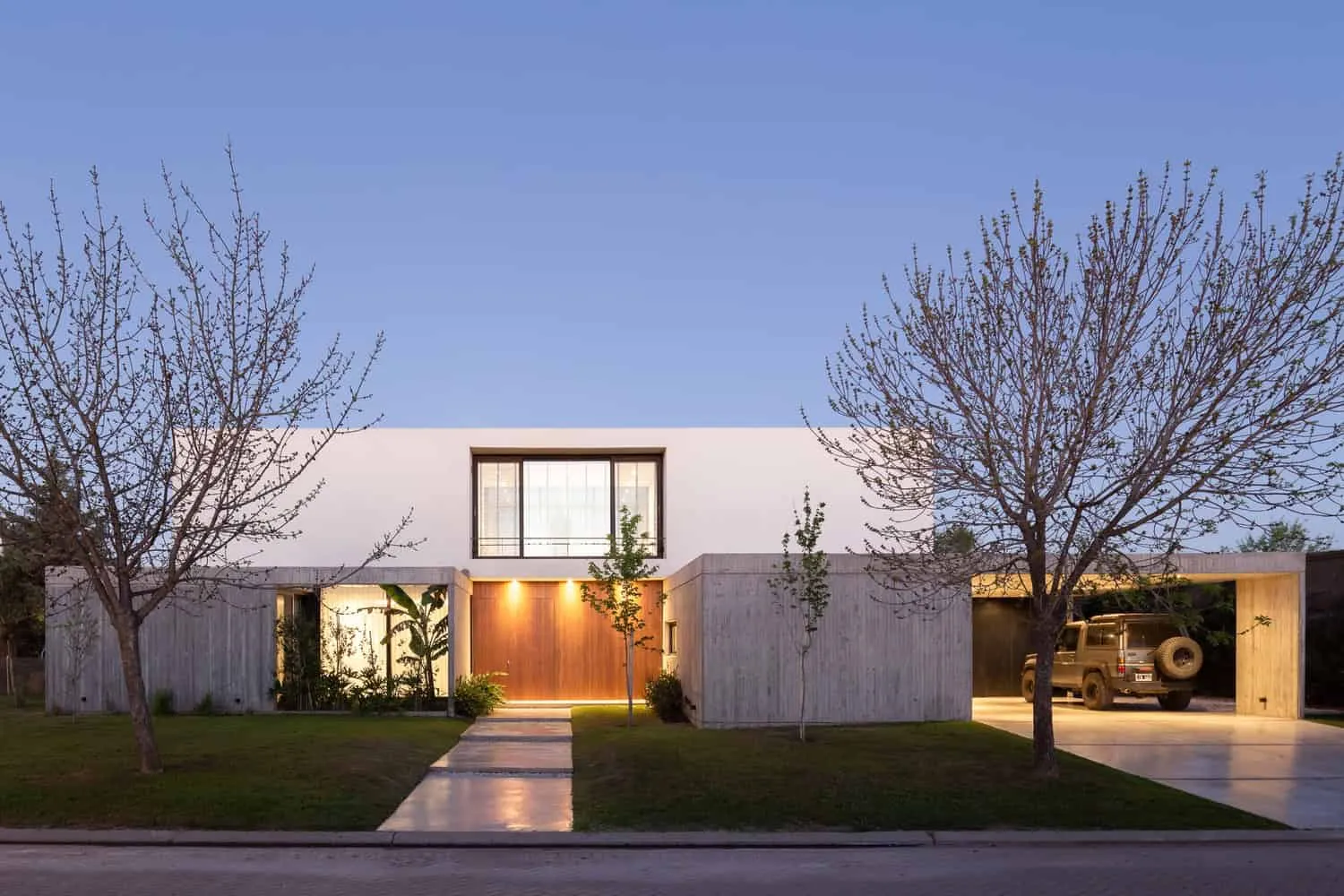 现代极简主义住宅，线条简洁、混凝土外墙和大窗户，被树木和精心打理的庭院环绕，展示创新建筑与时尚设计