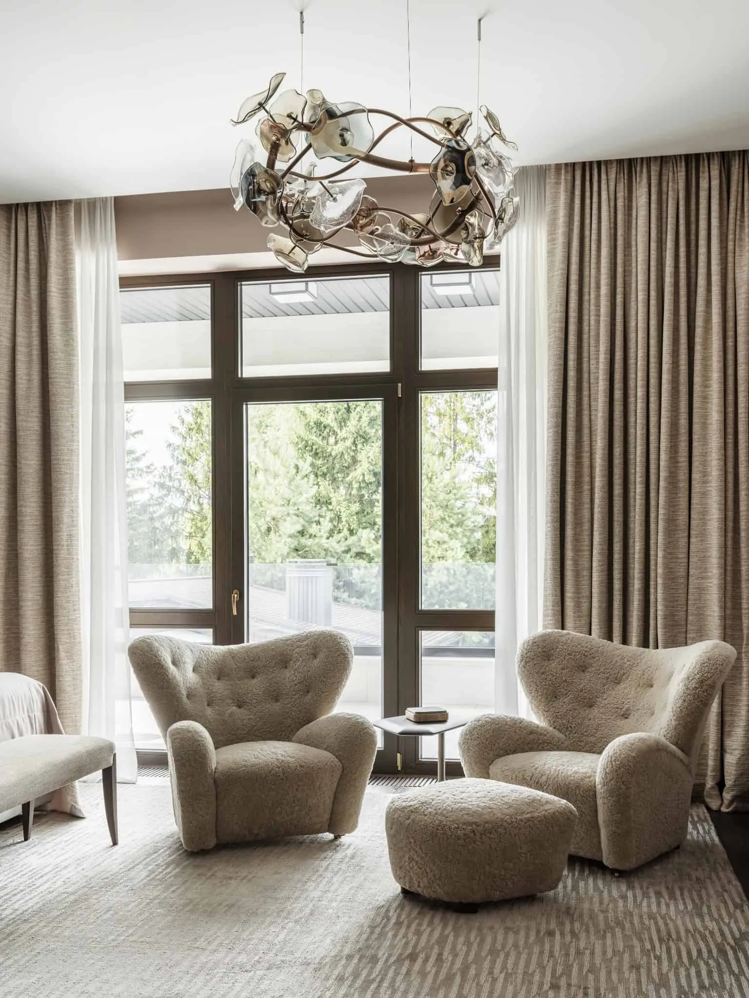 Зручне сидіння в кутку з пухнастими кріслами із вовни та скляною люстрою.