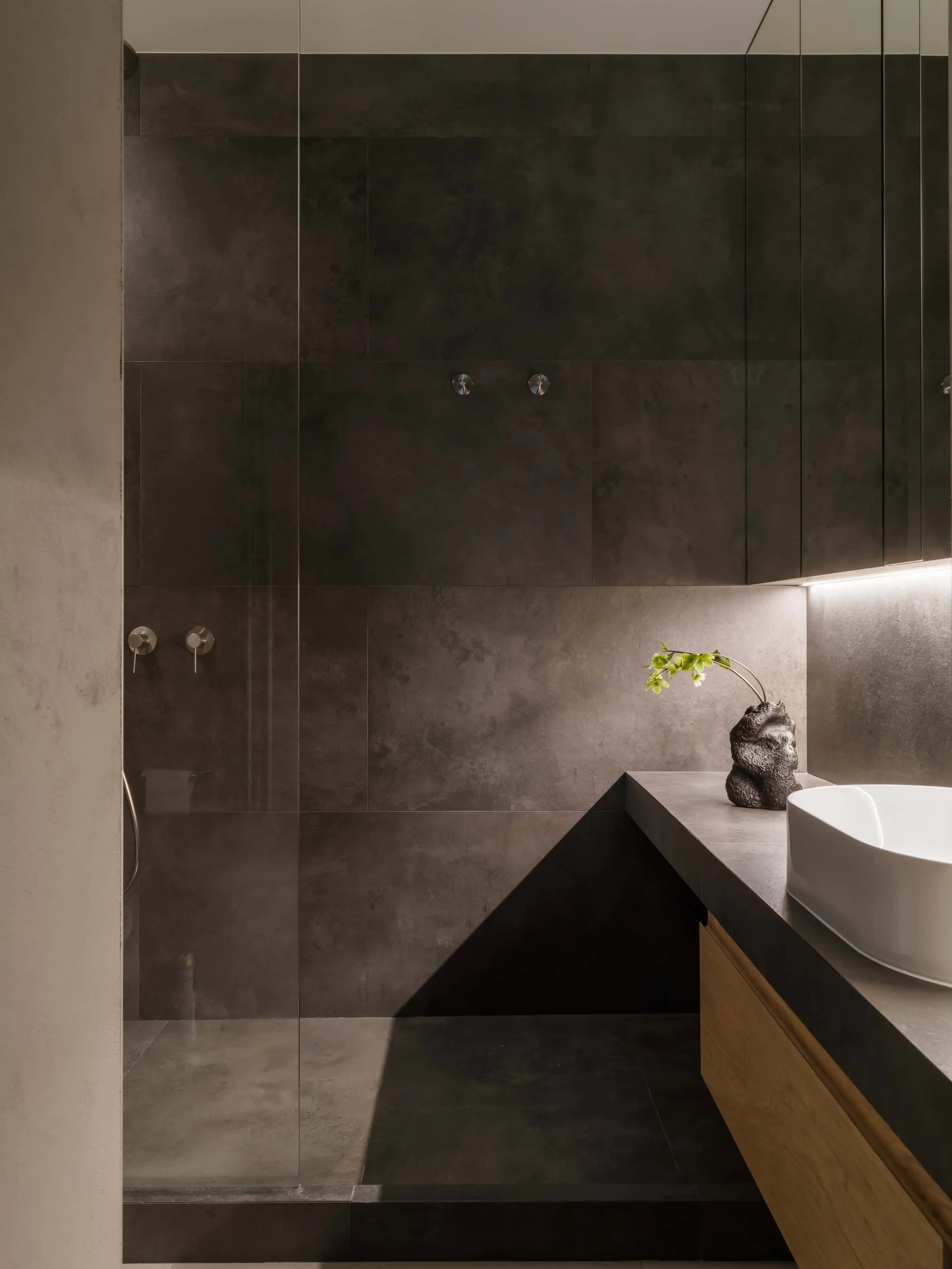 现代淋浴间，配深色哑光瓷砖与极简固定装置。
