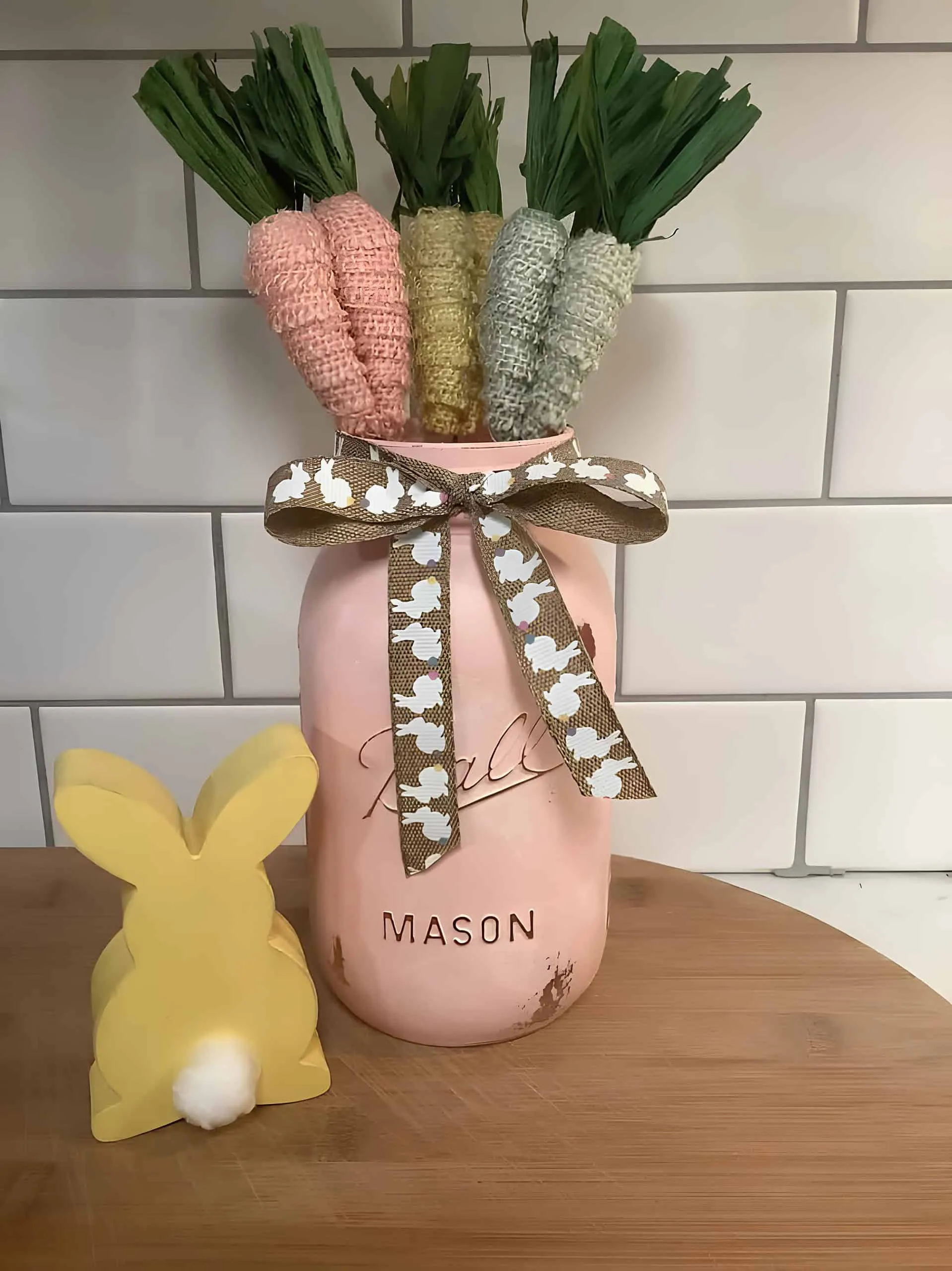 复活节粉色 Mason 罐子，胡萝卜胡须和兔子丝带，旁边是黄色木制小兔