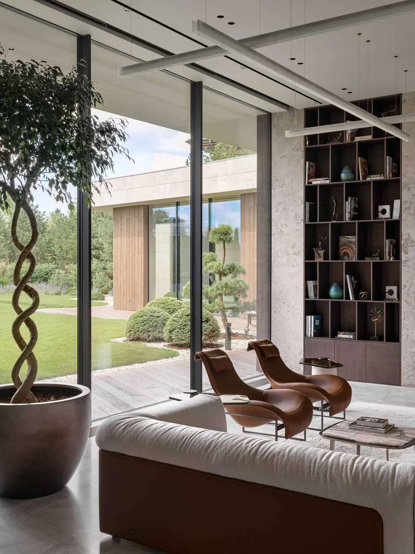 设计感扶手椅与高窗构成的温馨阅读角落，窗外是花园。