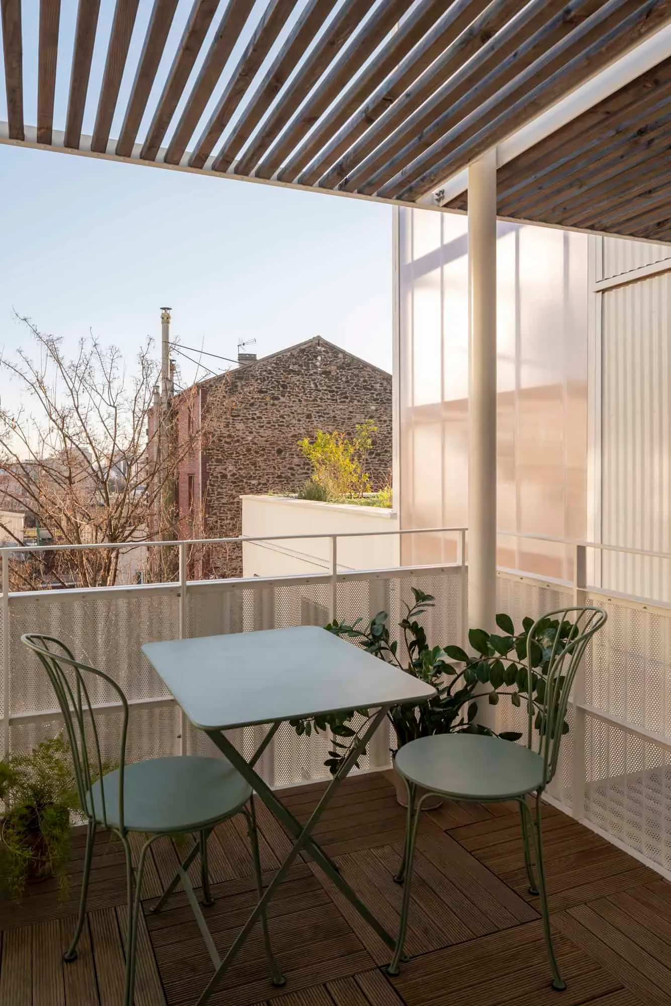 Relaxation area on the balcony with green metal chairs and urban landscape in background