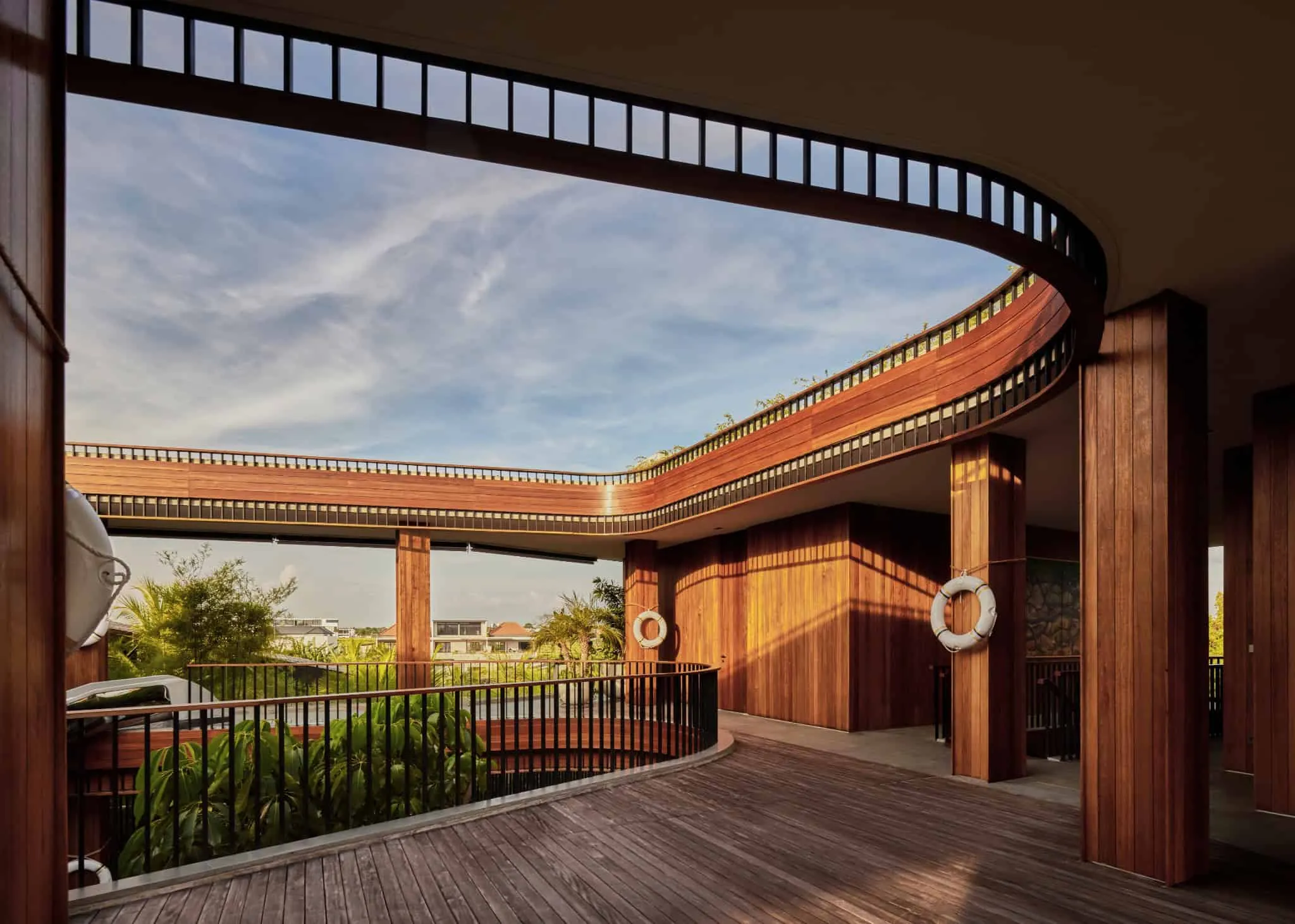 巴厘岛别墅阳台，夕阳金色光线和弯曲木质扶手。