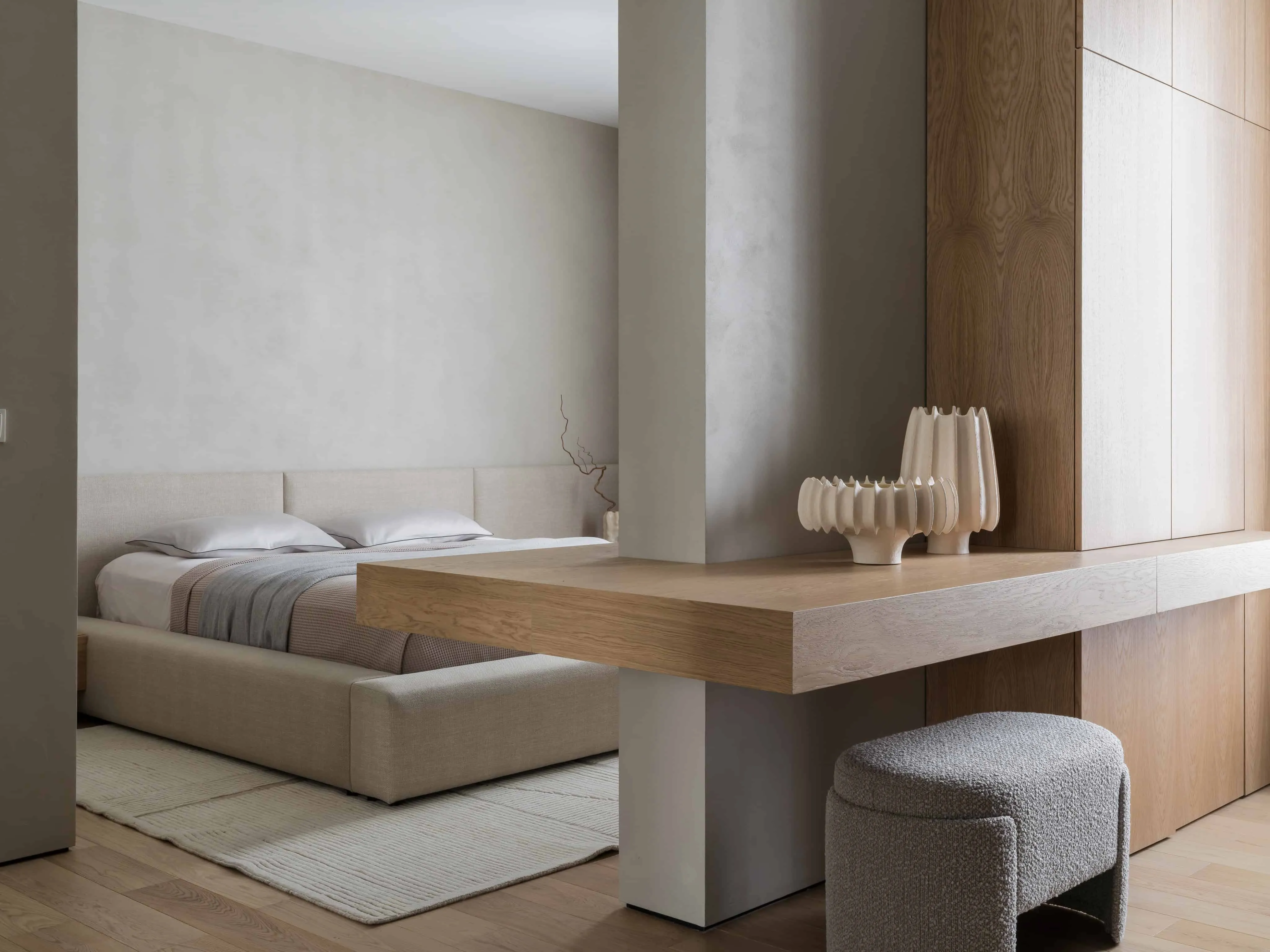 卧室中的漂浮木质洗手台，配雕塑花瓶与内置储物墙面。