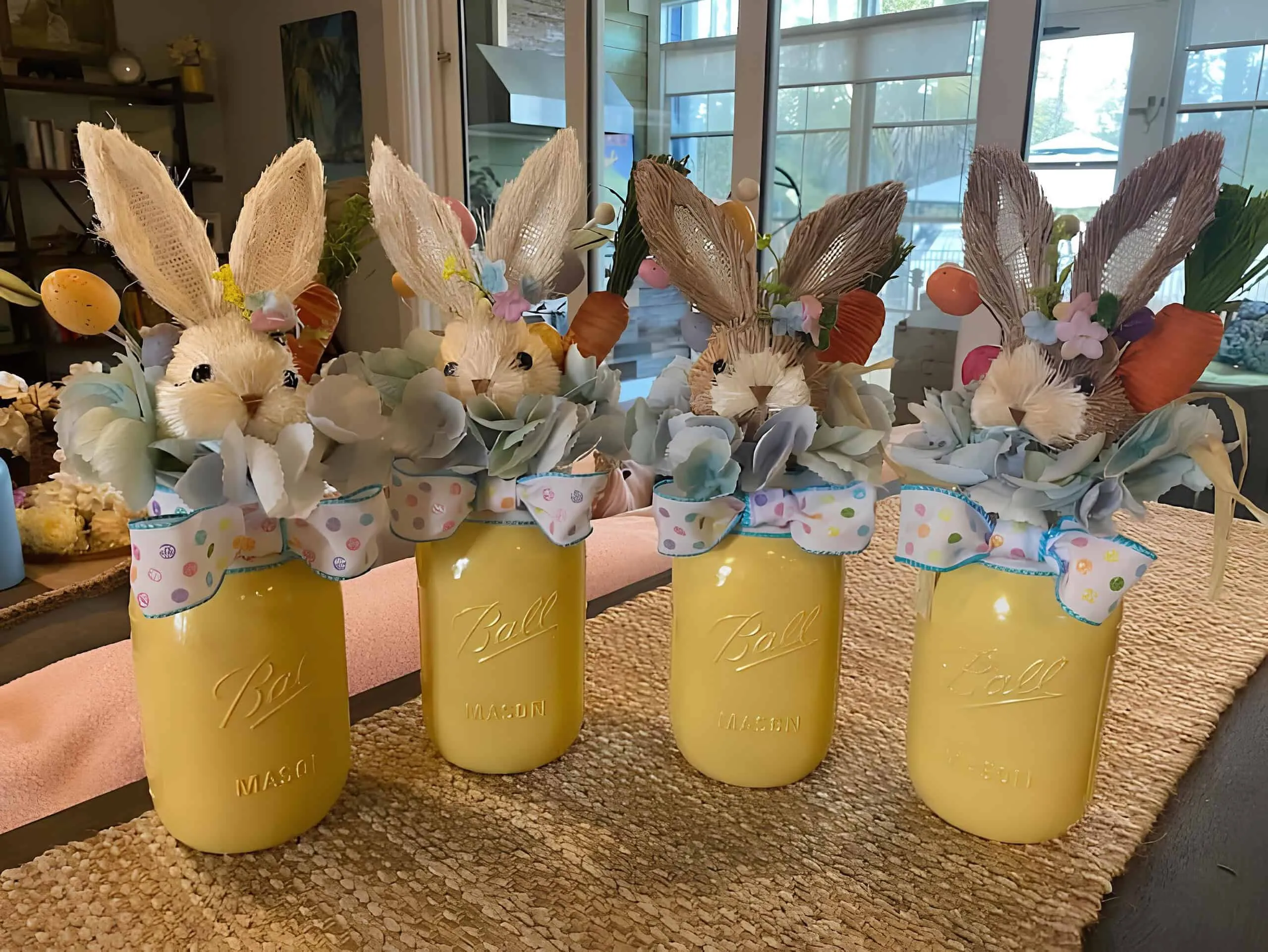 复活节黄色 Mason 罐子，有兔子头、柔和丝带、花和迷你胡萝卜作为春季中心装饰