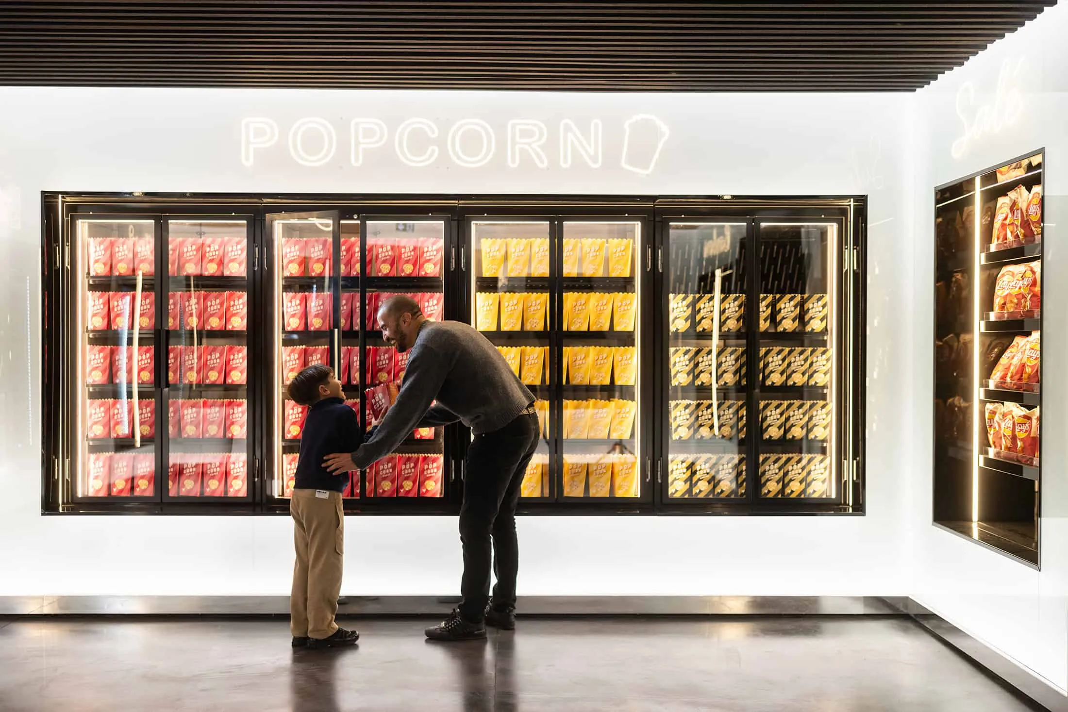 Father and son at a bright popcorn stand inside La Géode.