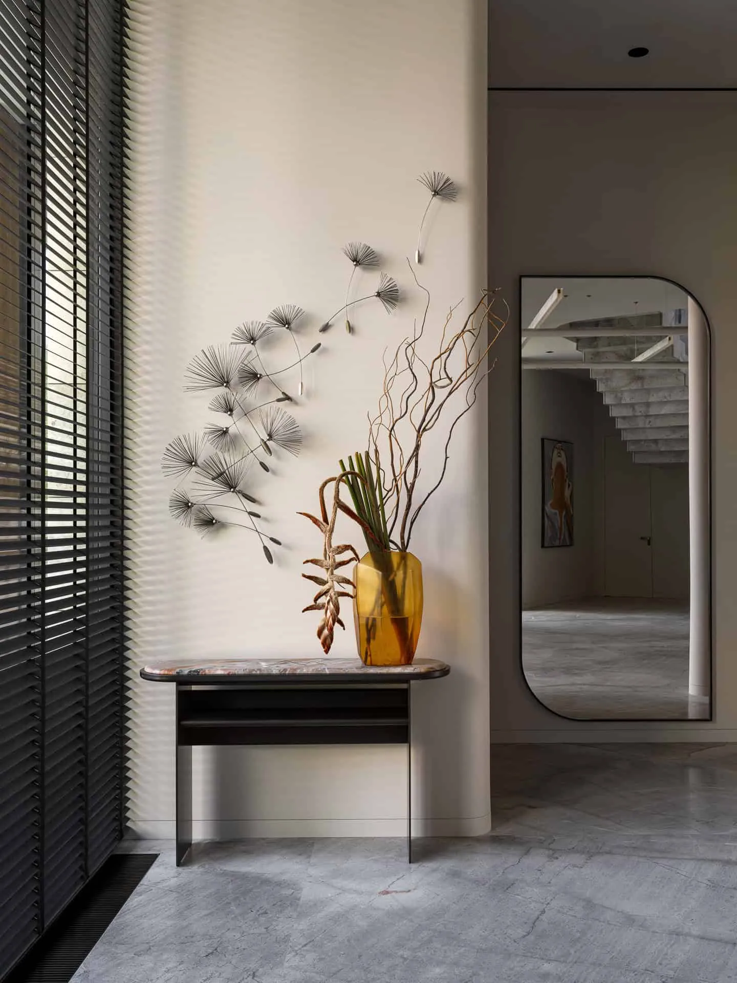 极简空间中黄色玻璃花瓶与雕塑干花的边桌。