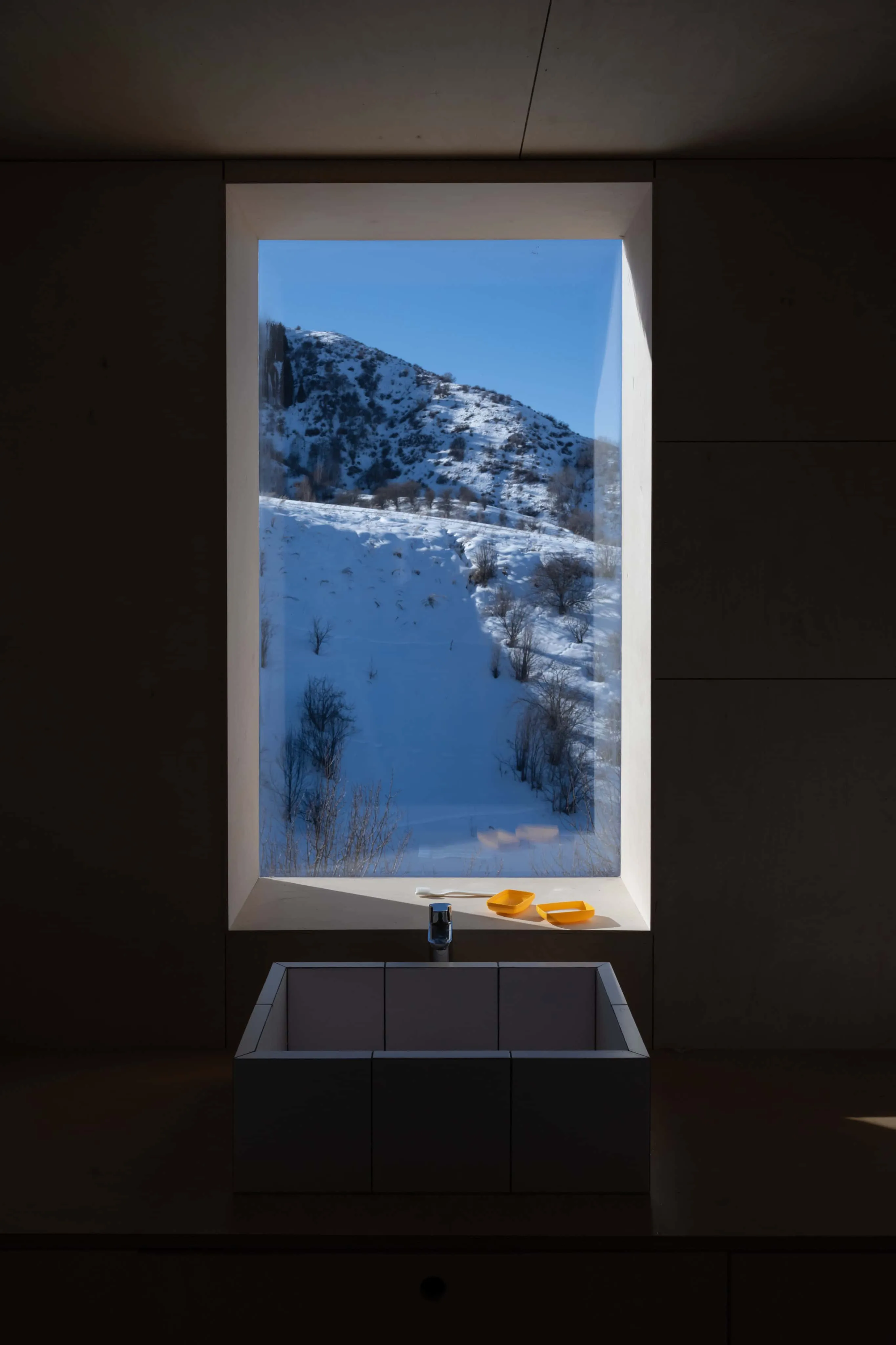 现代浴室窗户，框出美丽的雪坡风景。