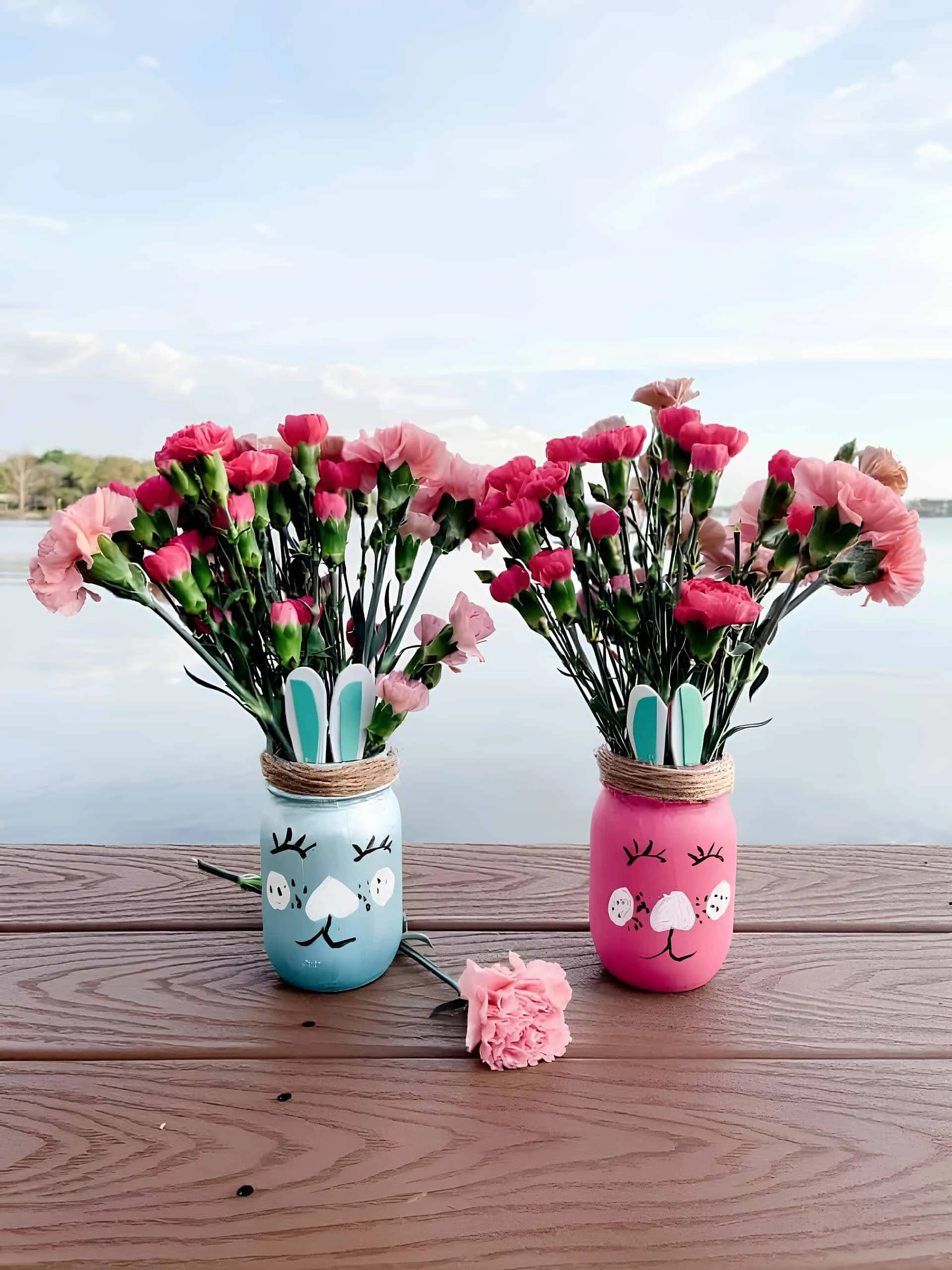 手工复活节 Mason 罐子，粉红色和蓝色涂色，装有石竹并装饰耳朵和绳子