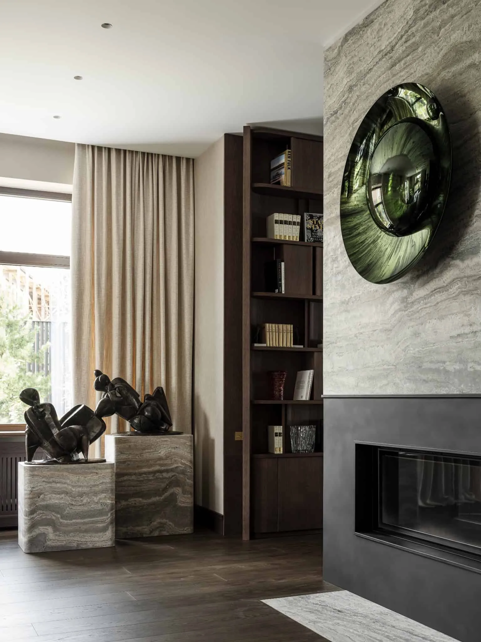 Елегантний кут гостинної з сучасним каміном і мраморними статуями на підставах.