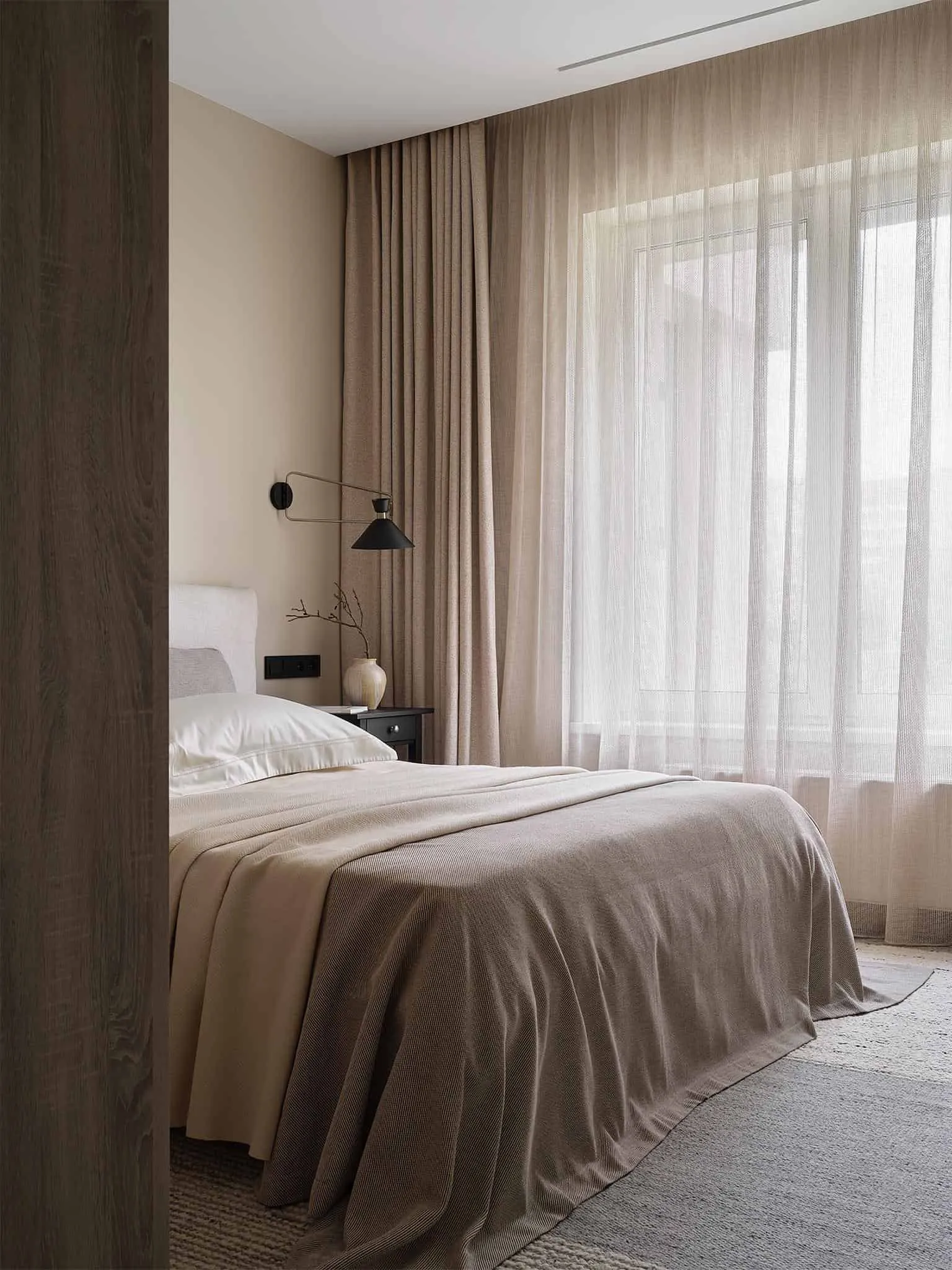 配有至天花板窗帘和层叠中性悬挂物的米色卧室。