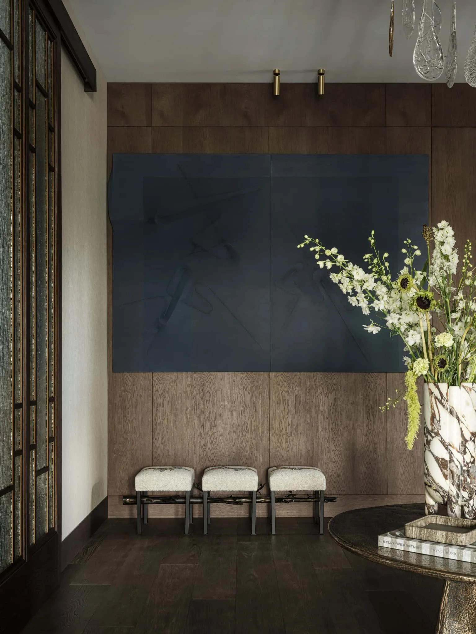 Набір із трьох обитих стільців під великим темно-синім абстрактним малюнком.